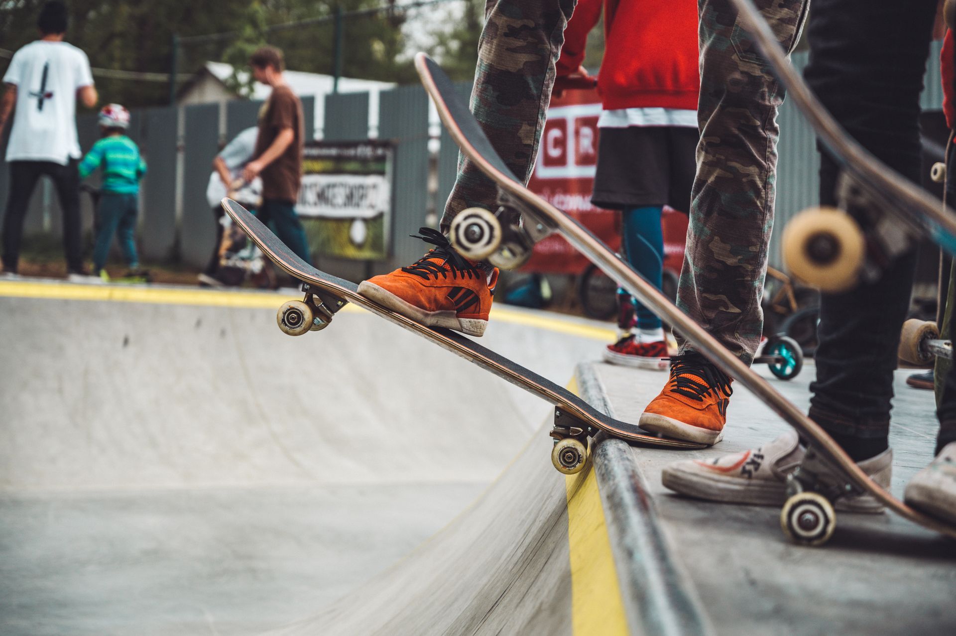 Skateboarders prepare to drop in on a small, concrete mini ramp.