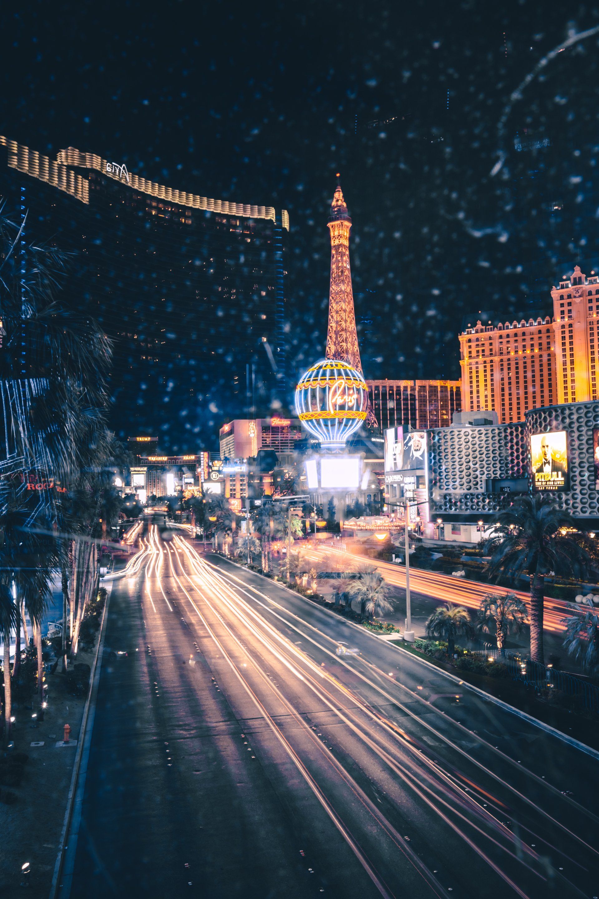 An aerial view of a city at night with a ferris wheel in the background.