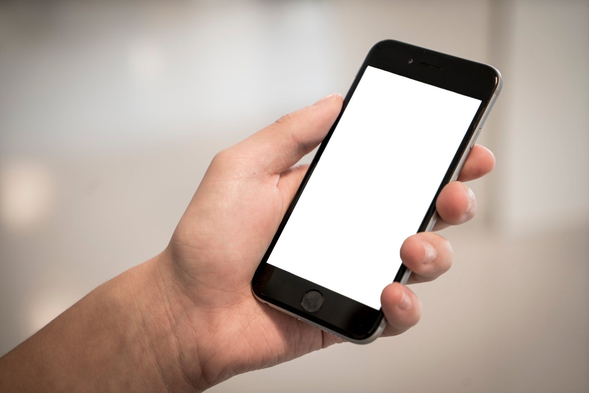 A person is holding a cell phone with a white screen.