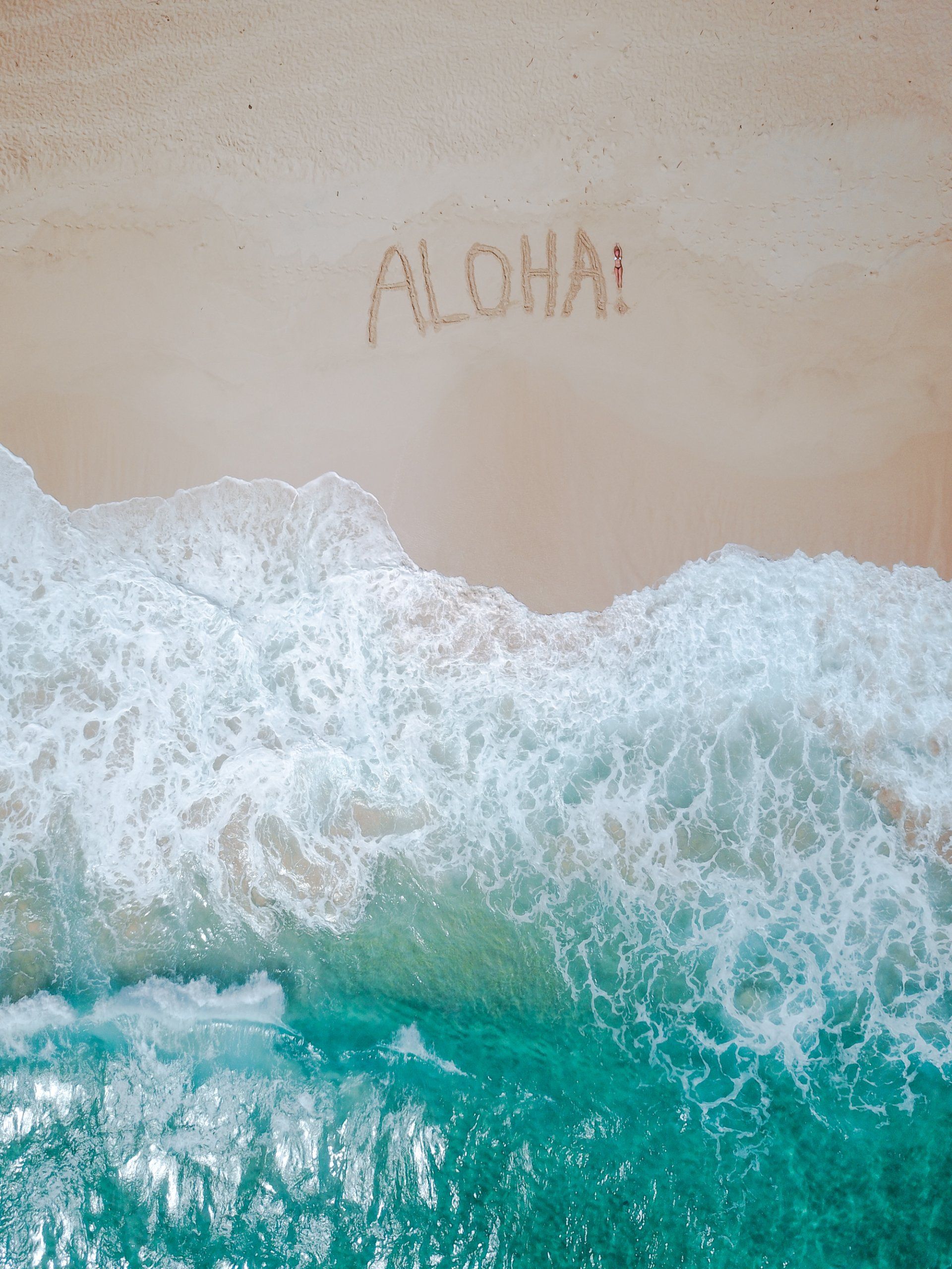 The word aloha is written in the sand on the beach.