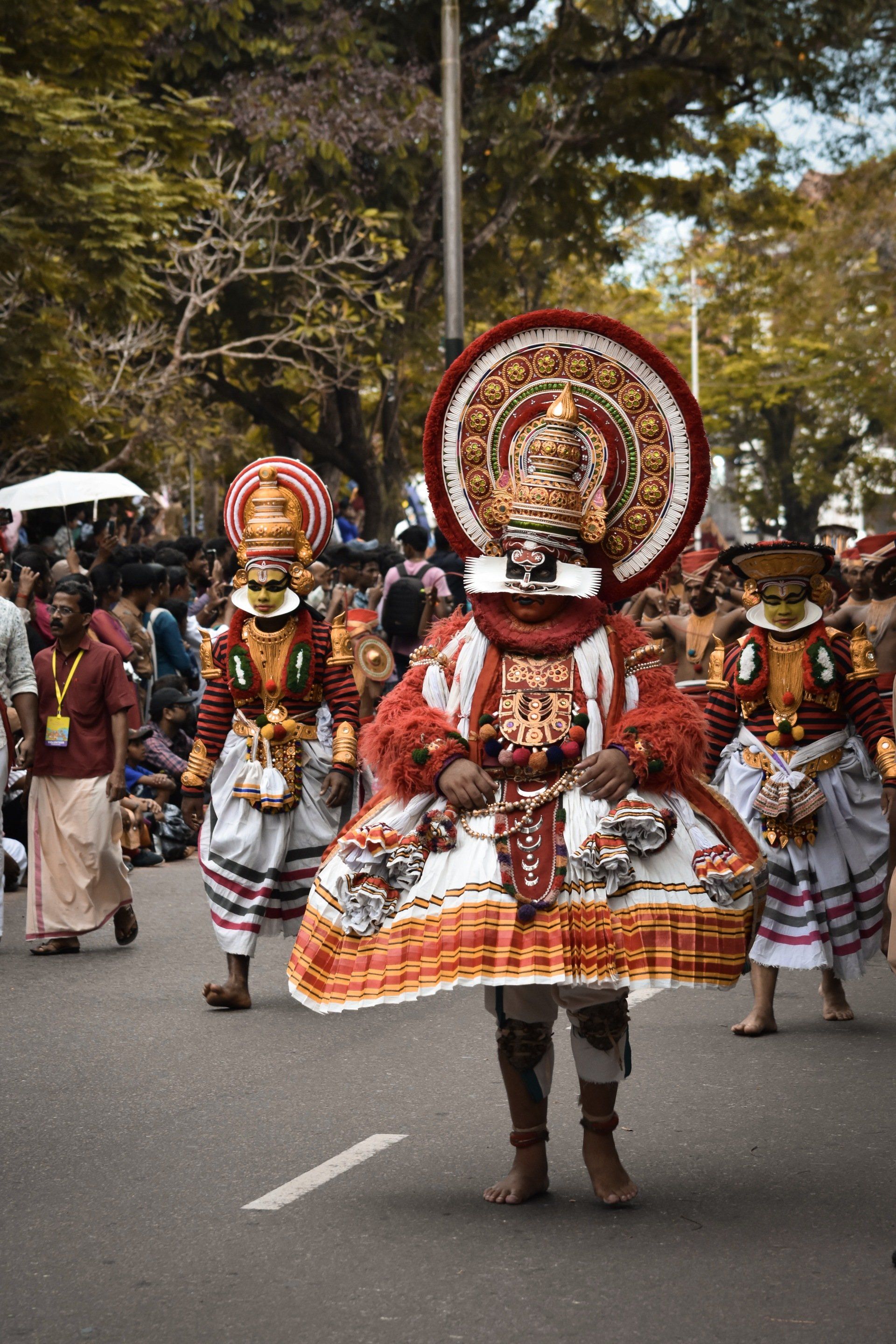 A group of people dressed in traditional costumes are walking down a street.