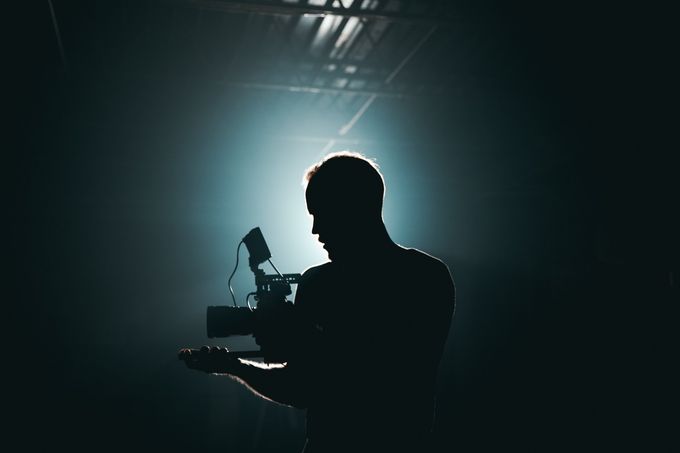 a silhouette of a man holding a camera in a dark room .