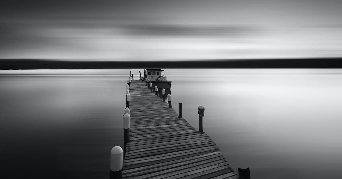 A black and white photo of a dock in the middle of a lake.