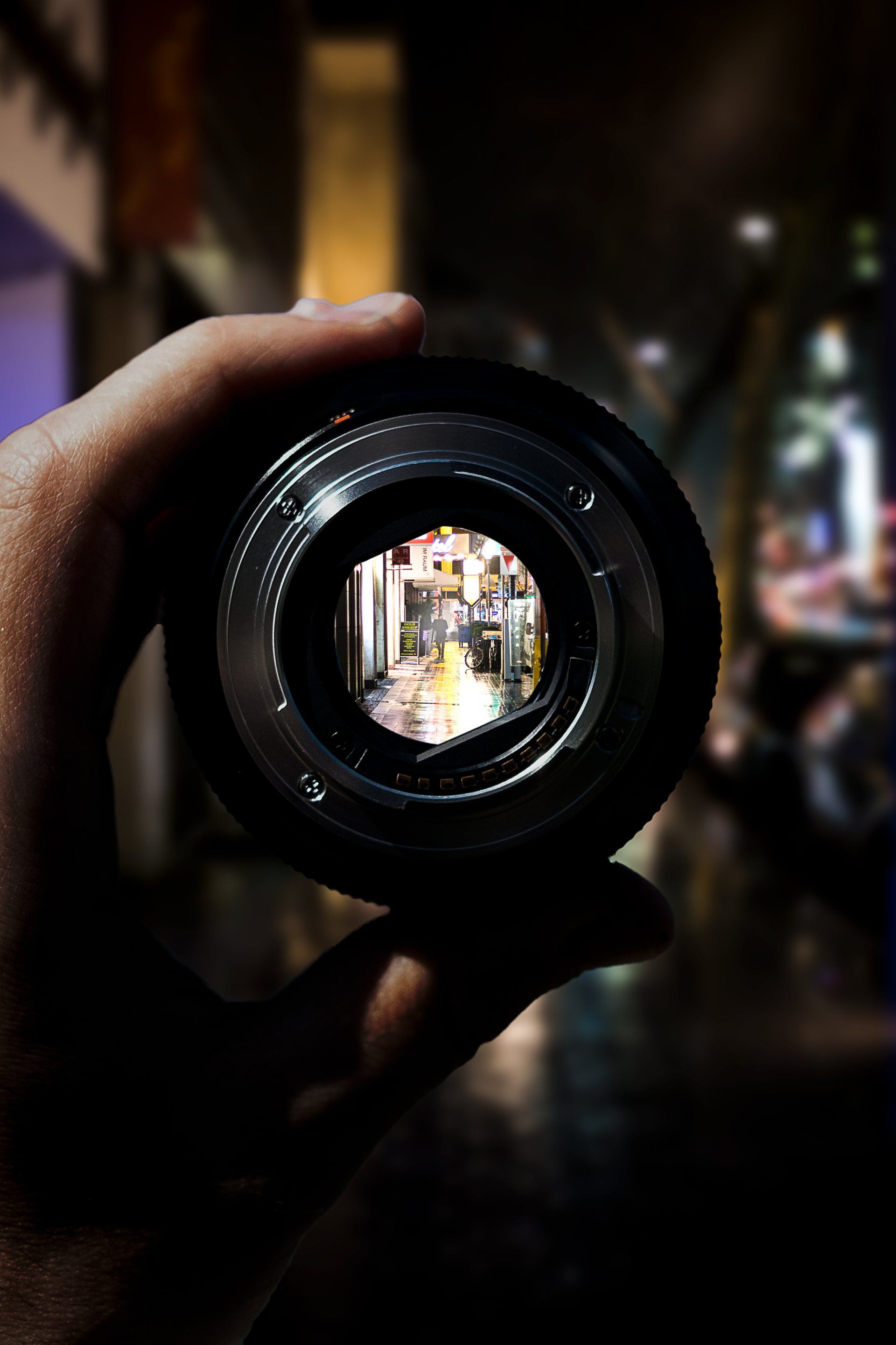 A person is holding a camera lens in their hand and looking through it.