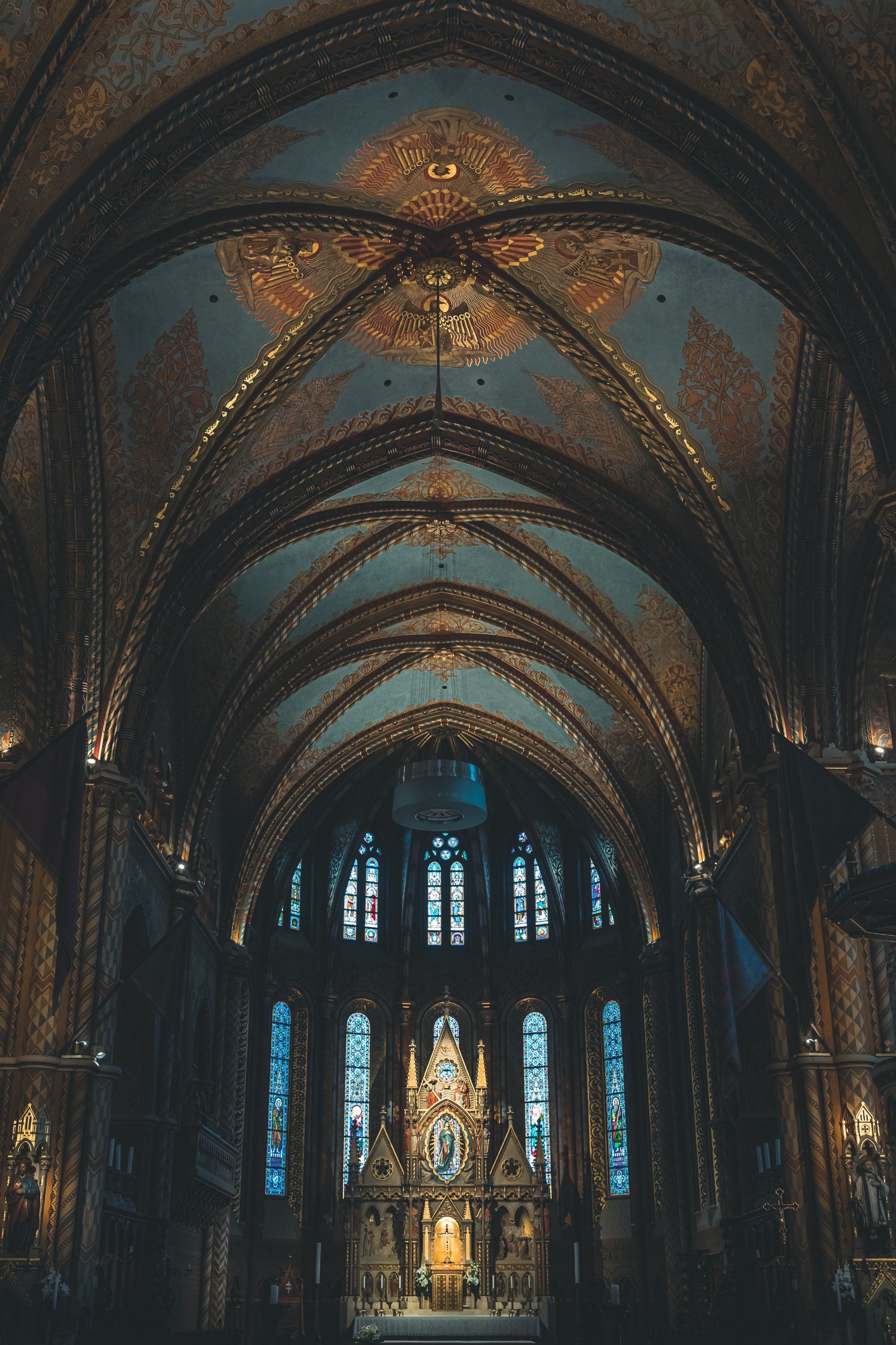The inside of a church with a blue ceiling and stained glass windows.