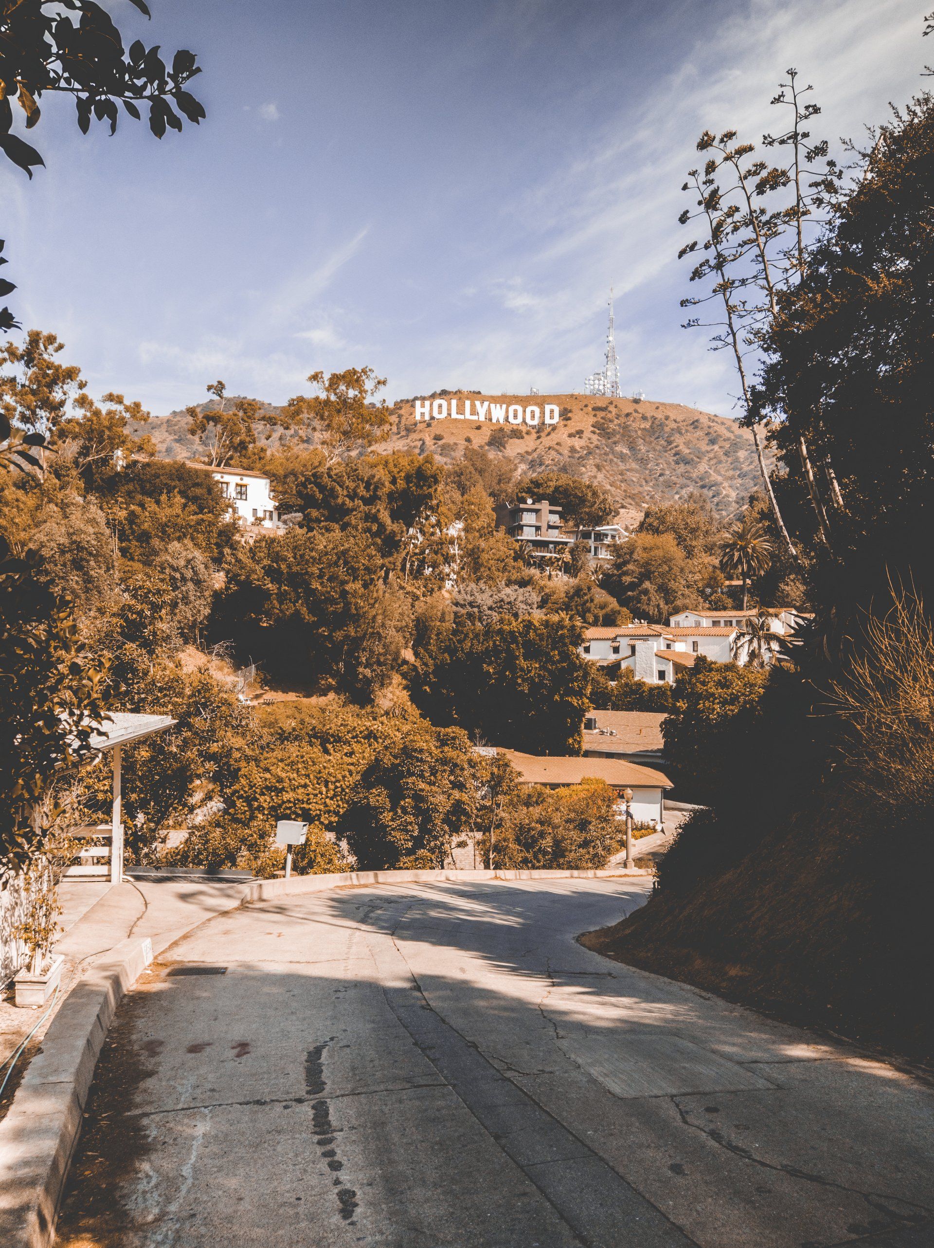 A road going towards the hollywood sign on top of a hill