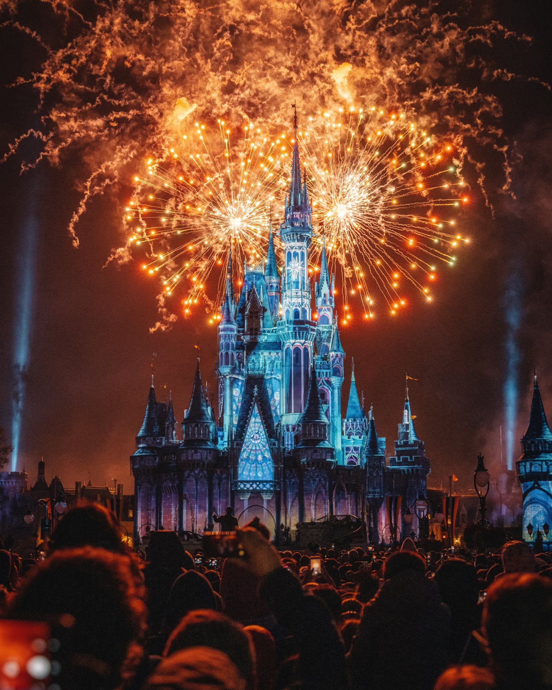 Een menigte mensen kijkt naar vuurwerk boven een kasteel.