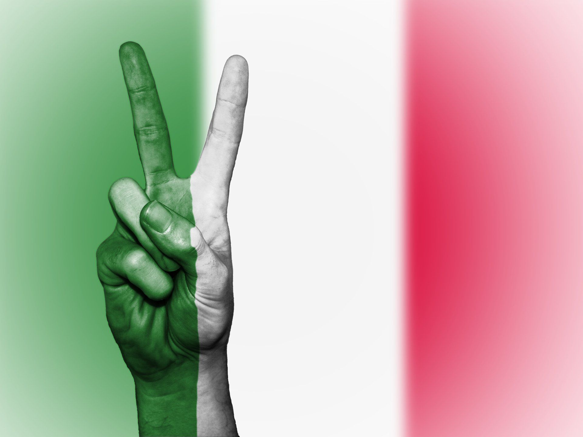 una mano dipinta con i colori della bandiera italiana fa un segno di pace .