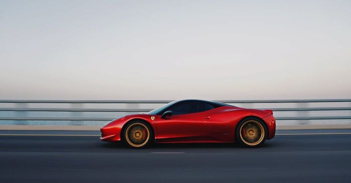 A red sports car is driving down a highway.