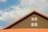 A house with a red roof and a blue sky in the background