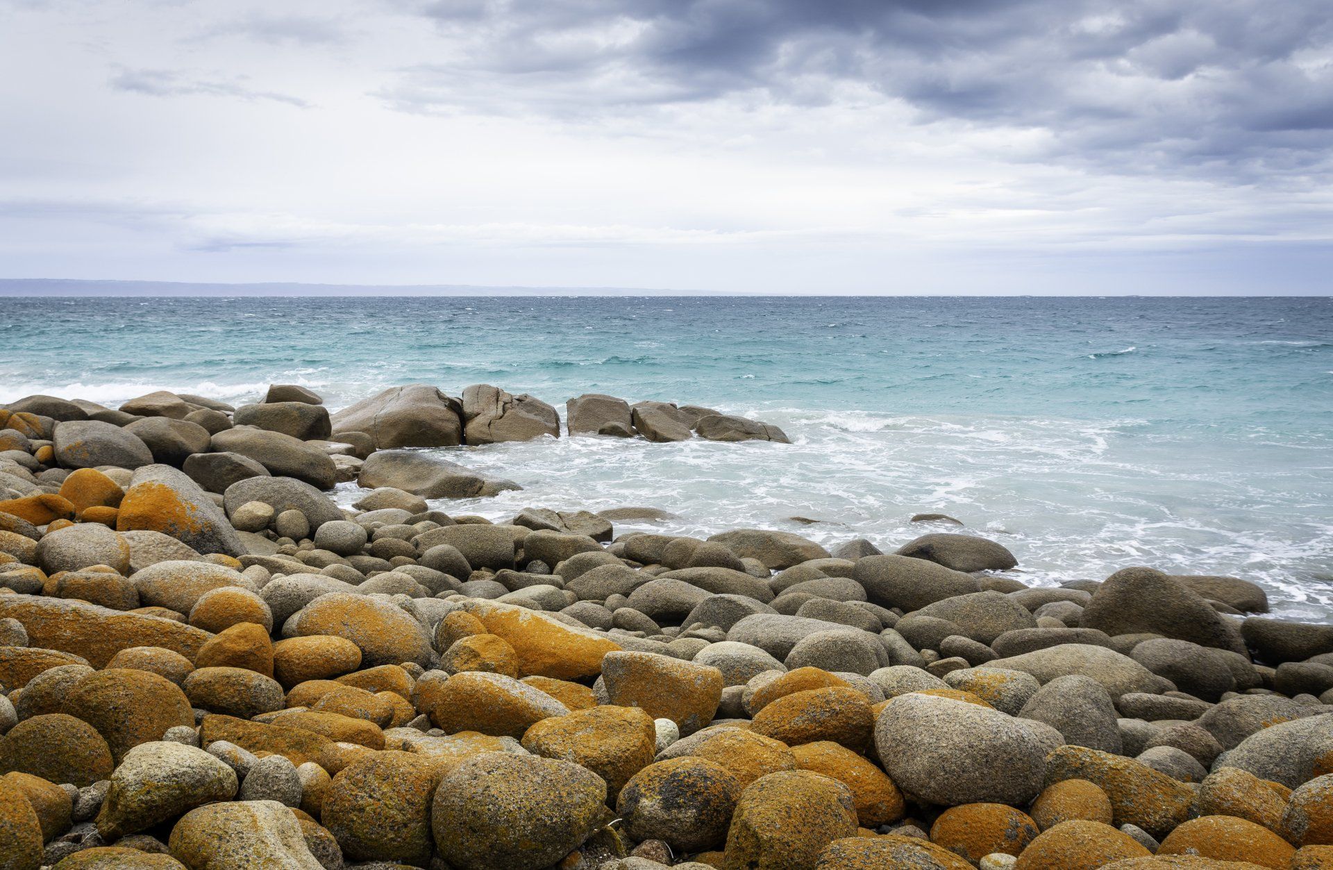 A rocky beach with a large body of water in the background.