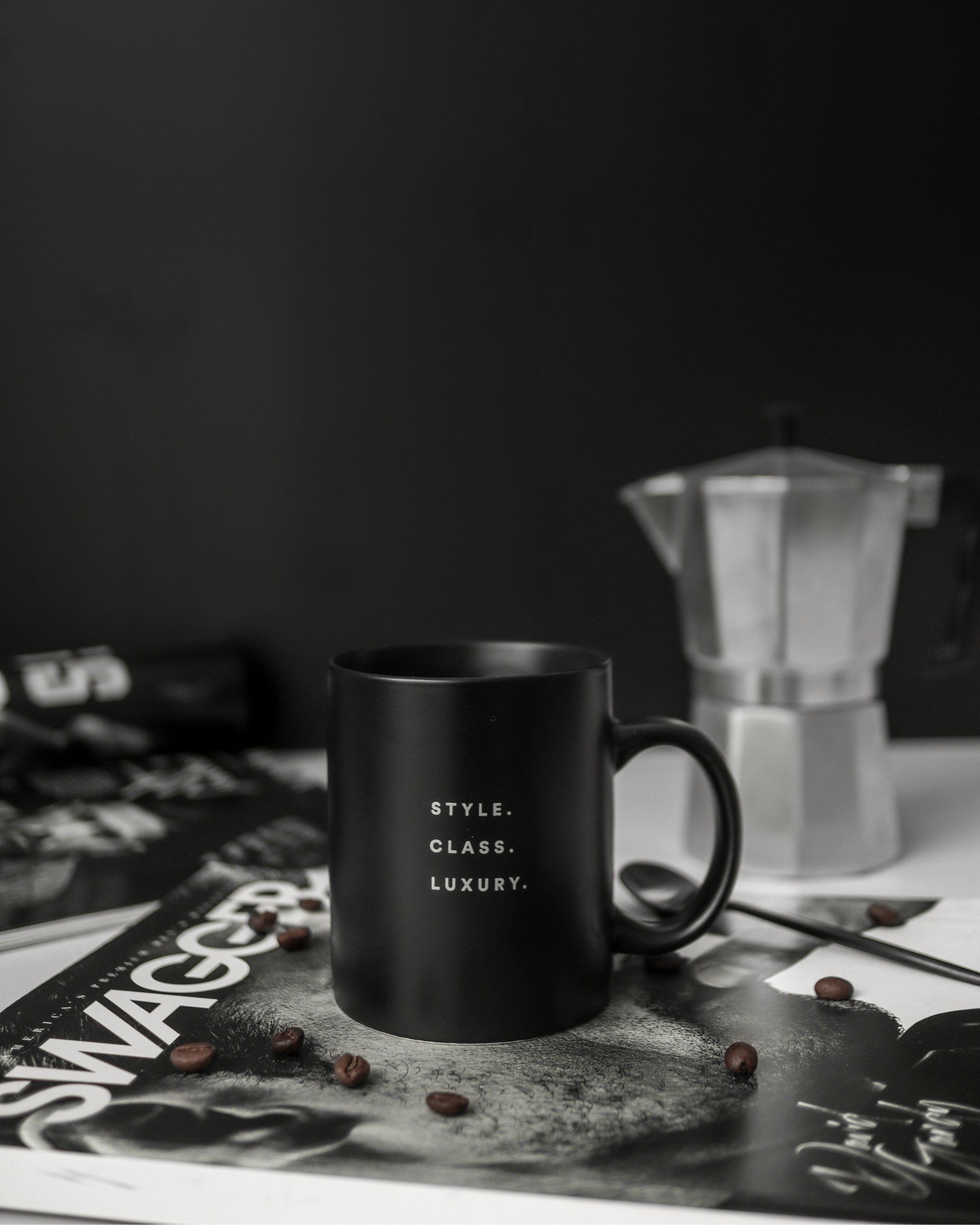 A black coffee mug is sitting on top of a magazine on a table.