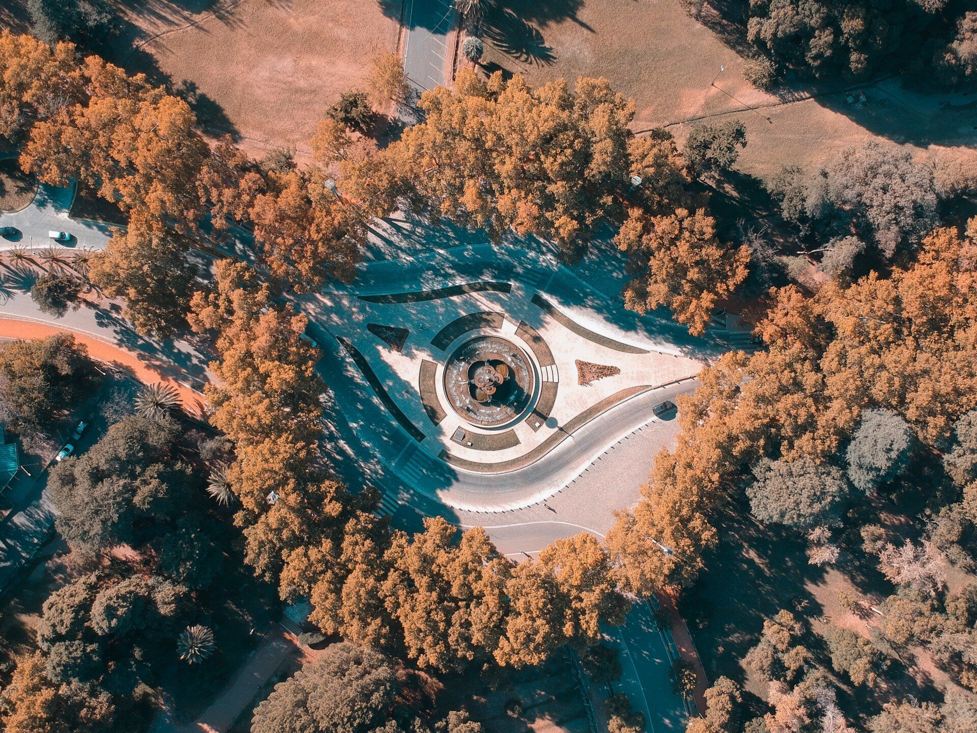 An aerial view of a roundabout surrounded by trees and a road.
