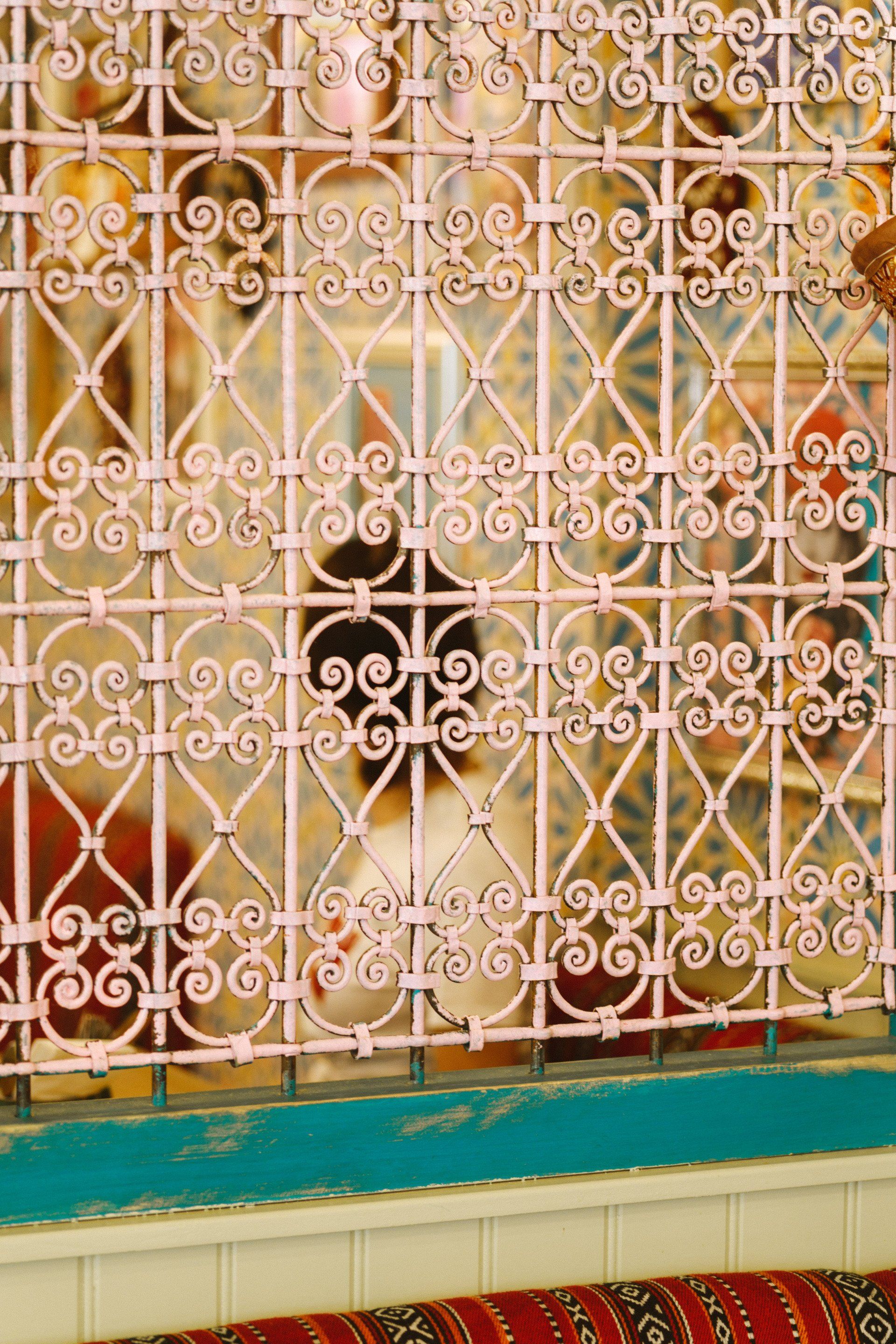 A close up of a wrought iron fence behind a window.