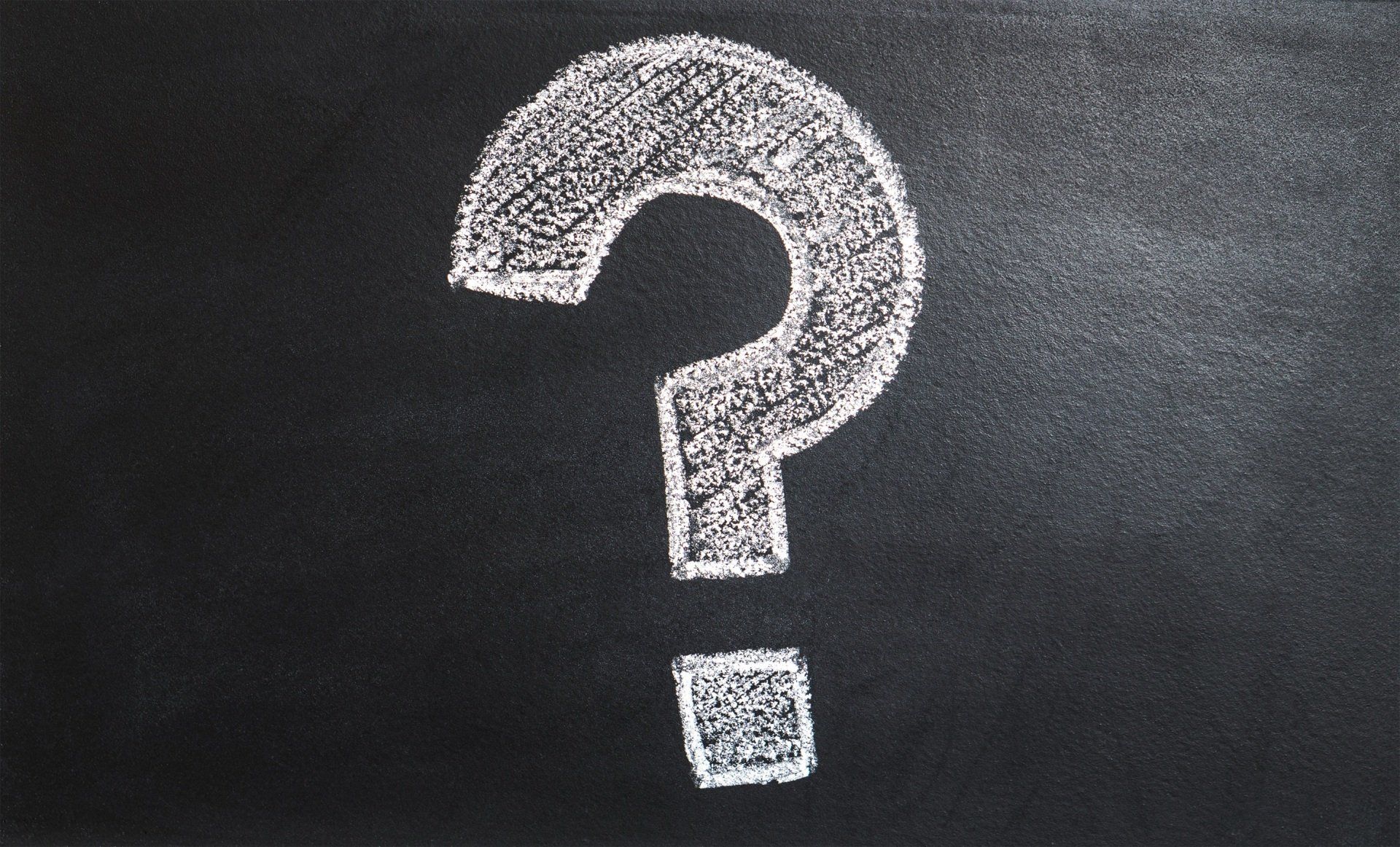 A question mark is drawn on a blackboard with chalk.
