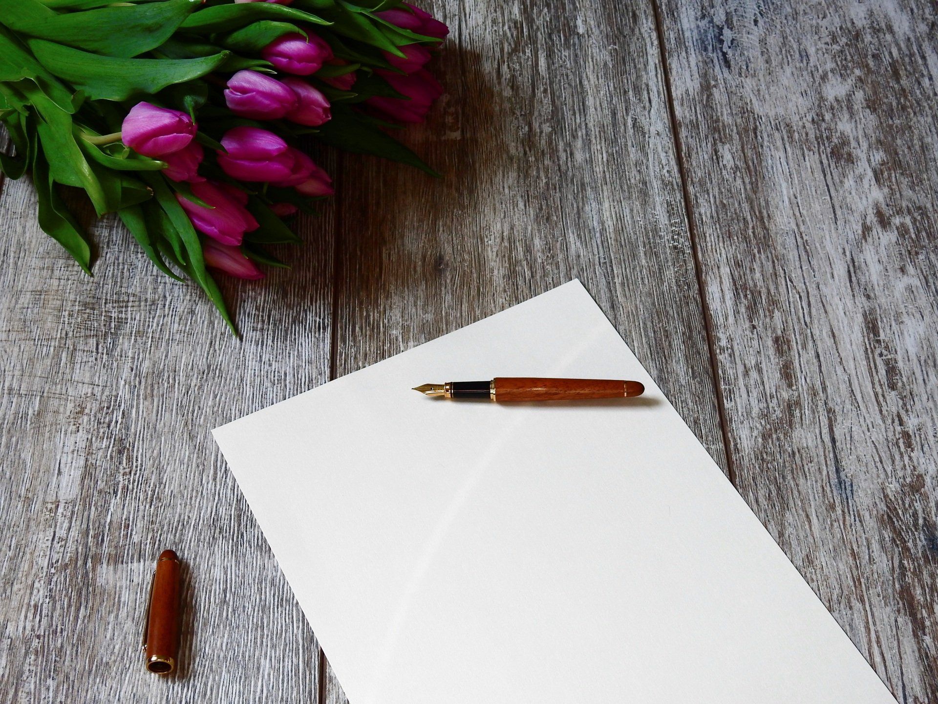 a pen sits on a piece of paper next to a bouquet of pink flowers