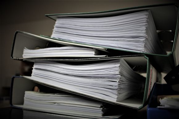 A stack of binders filled with papers on a table.