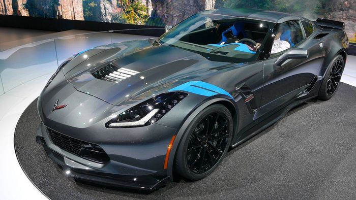 A gray sports car with a blue stripe on the side is on display at a car show.
