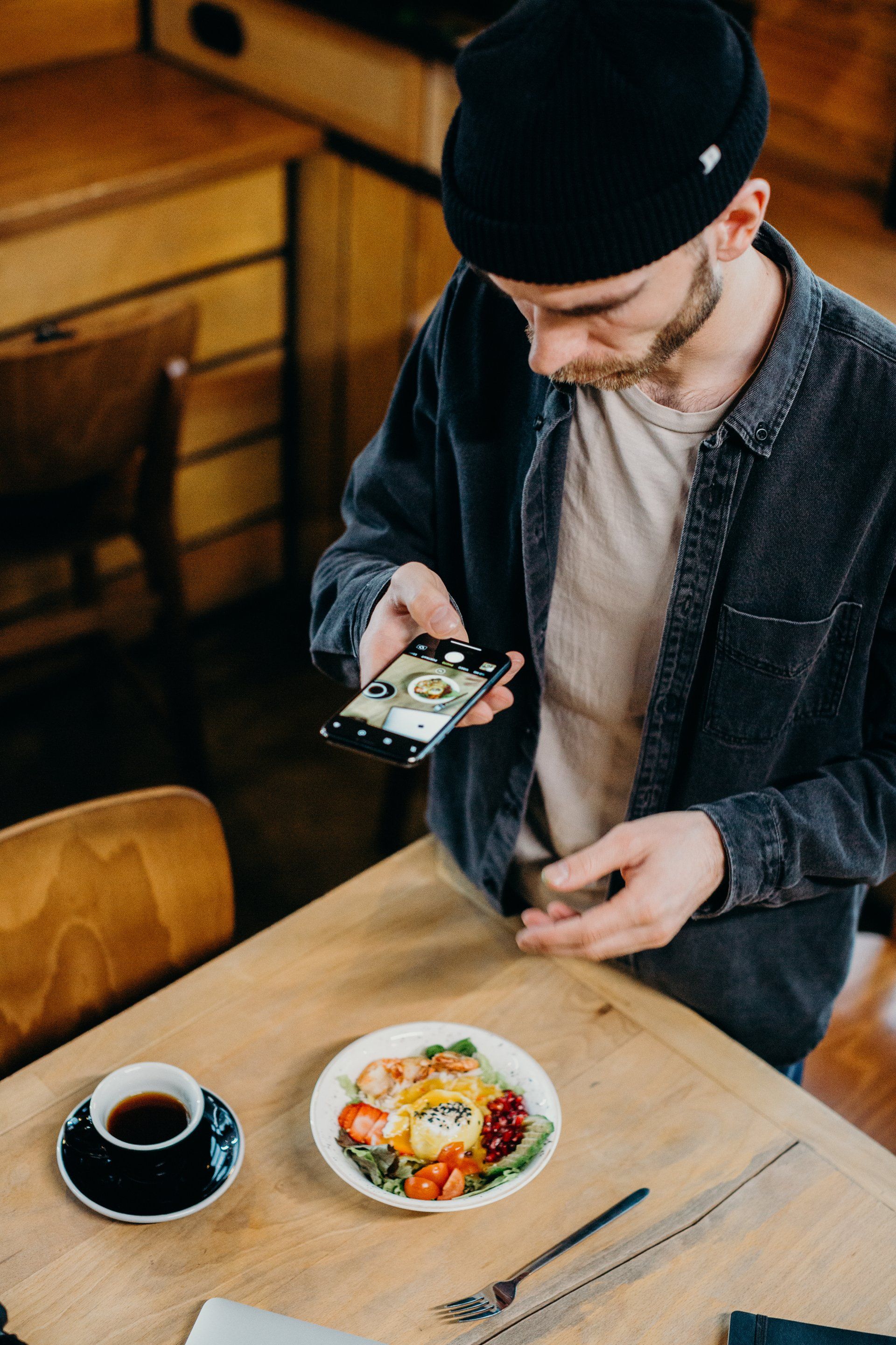 A man is sitting at a table taking a picture of a plate of food.