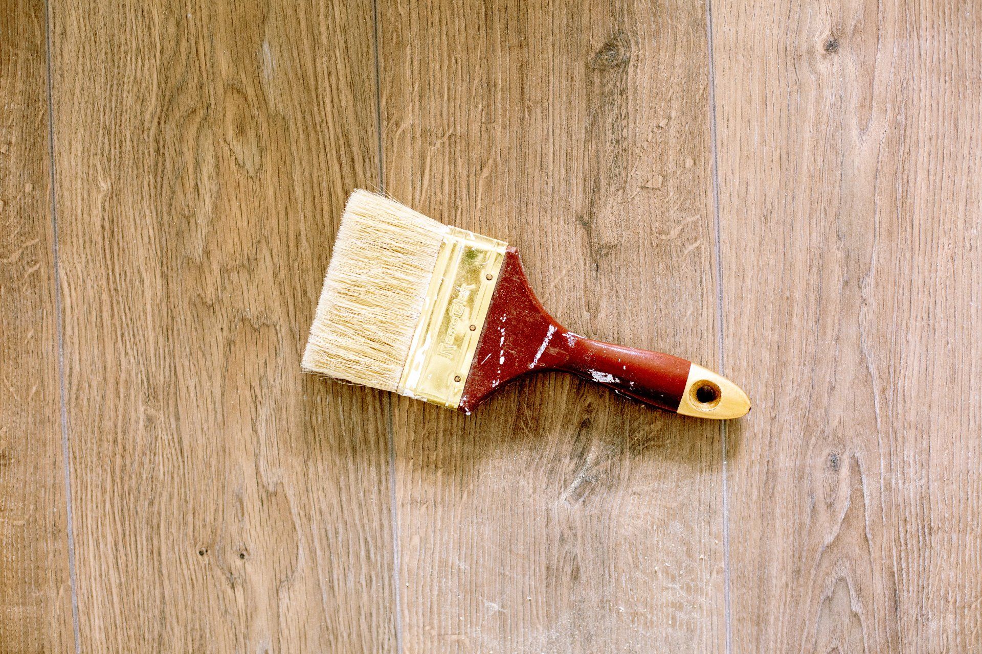 A paintbrush on a wooden floor of a Vermont home that is undergoing improvments