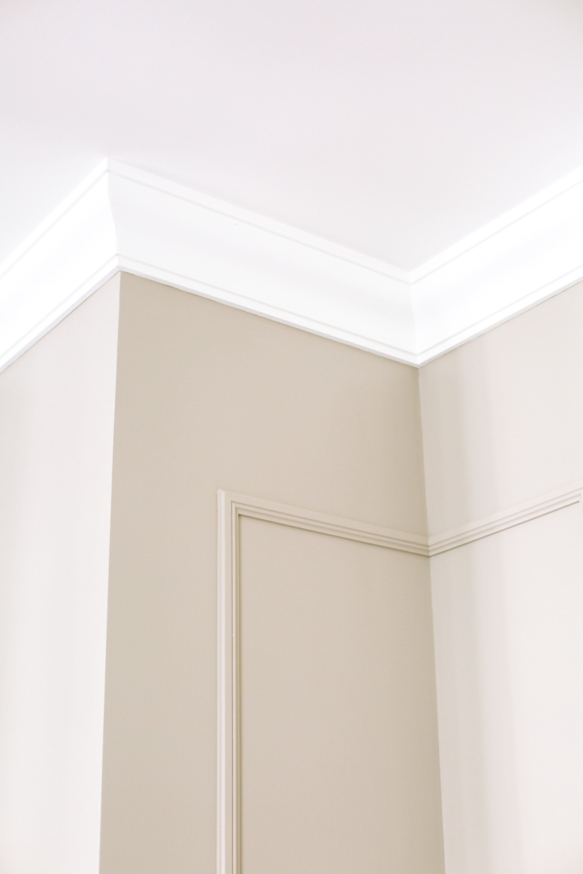 A beige wall with molding glued on and painted to match for DIY wainscoting