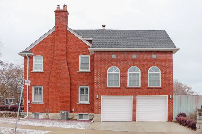 A large red brick house with white garage doors and arched windows