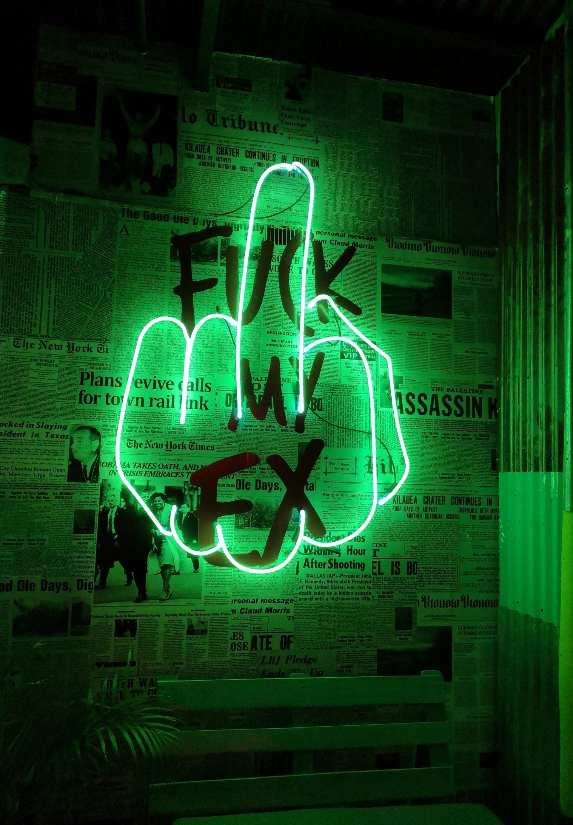 neonbelysning i grönt föreställande en hand som ger fingret