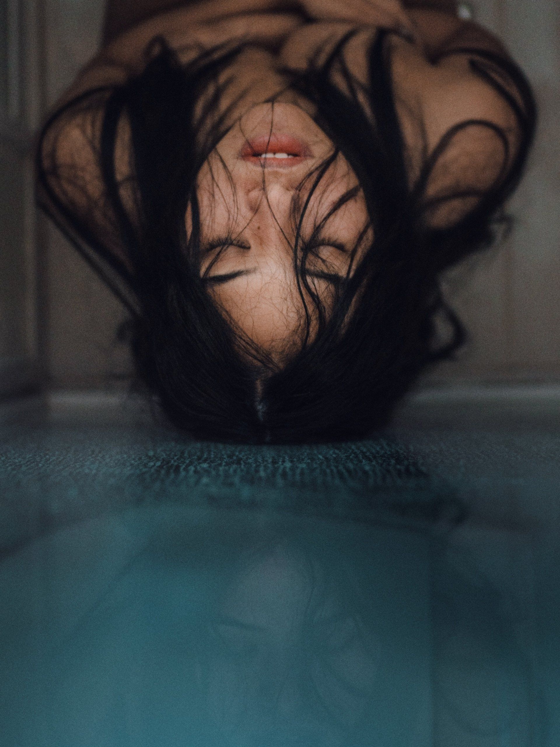 A woman is laying in a bathtub with her head in the water.