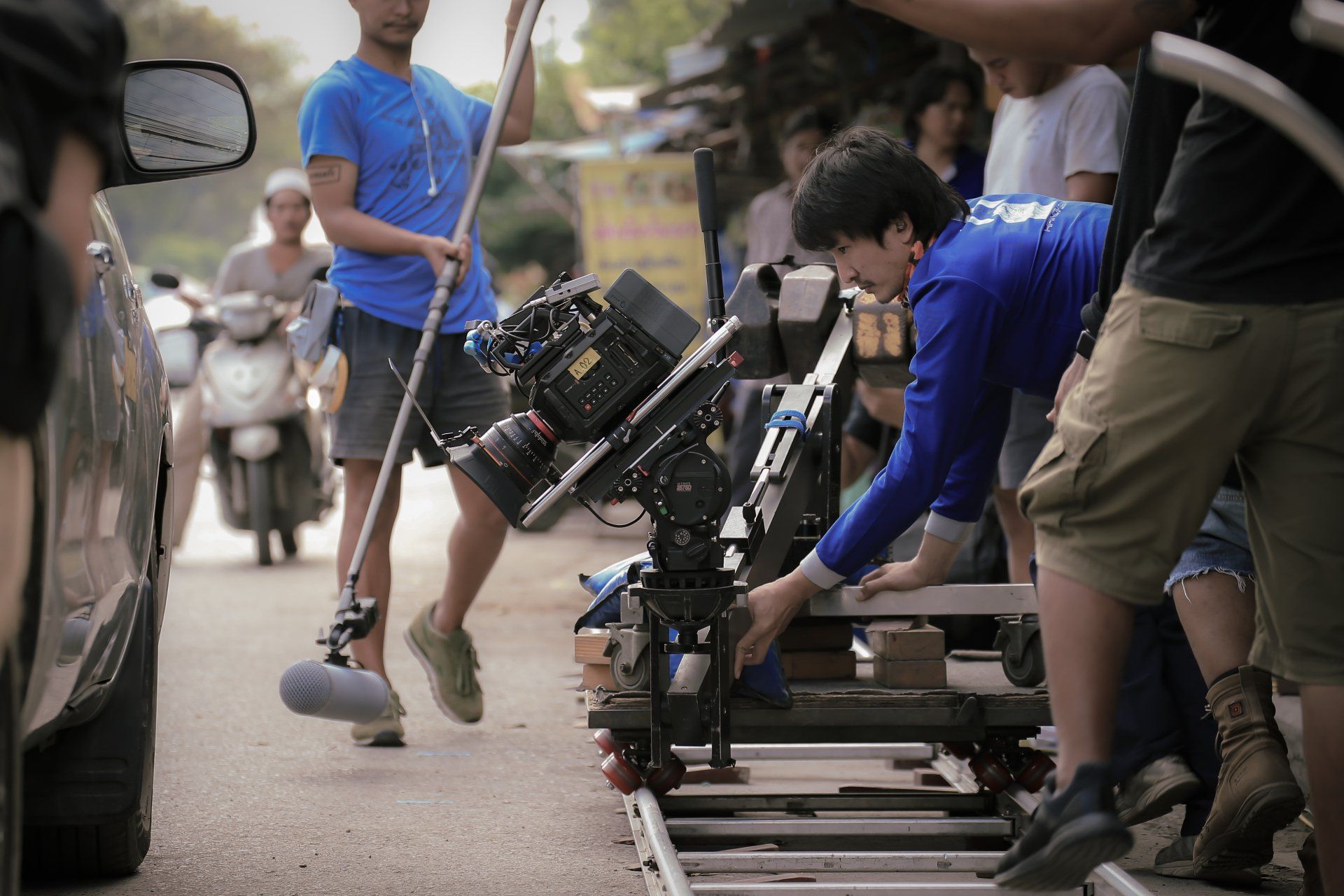 Film production crew members in blue shirts set up a film camera for a shot