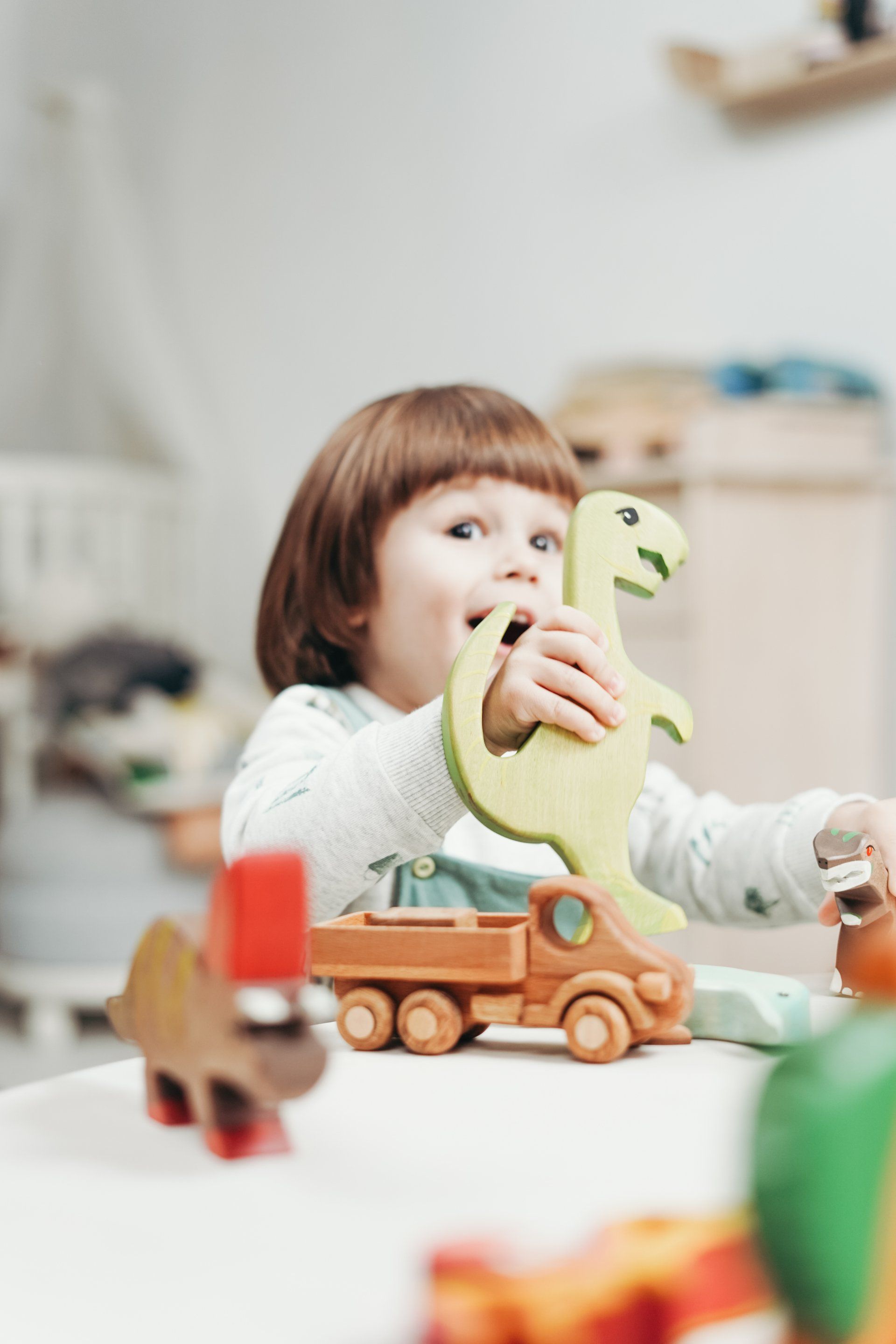 A little girl is sitting at a table playing with wooden toys.