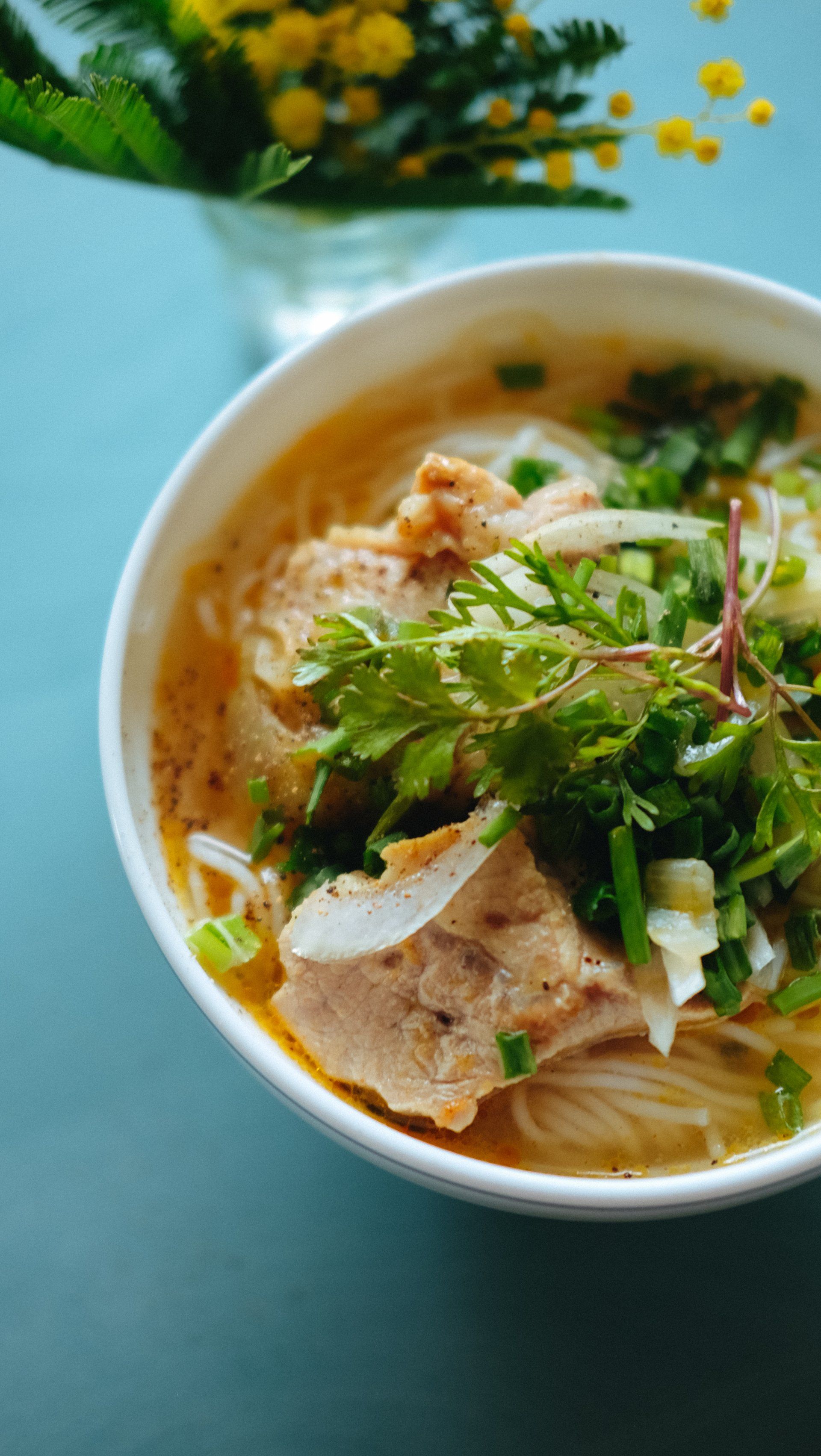 A bowl of soup with meat and noodles on a table.