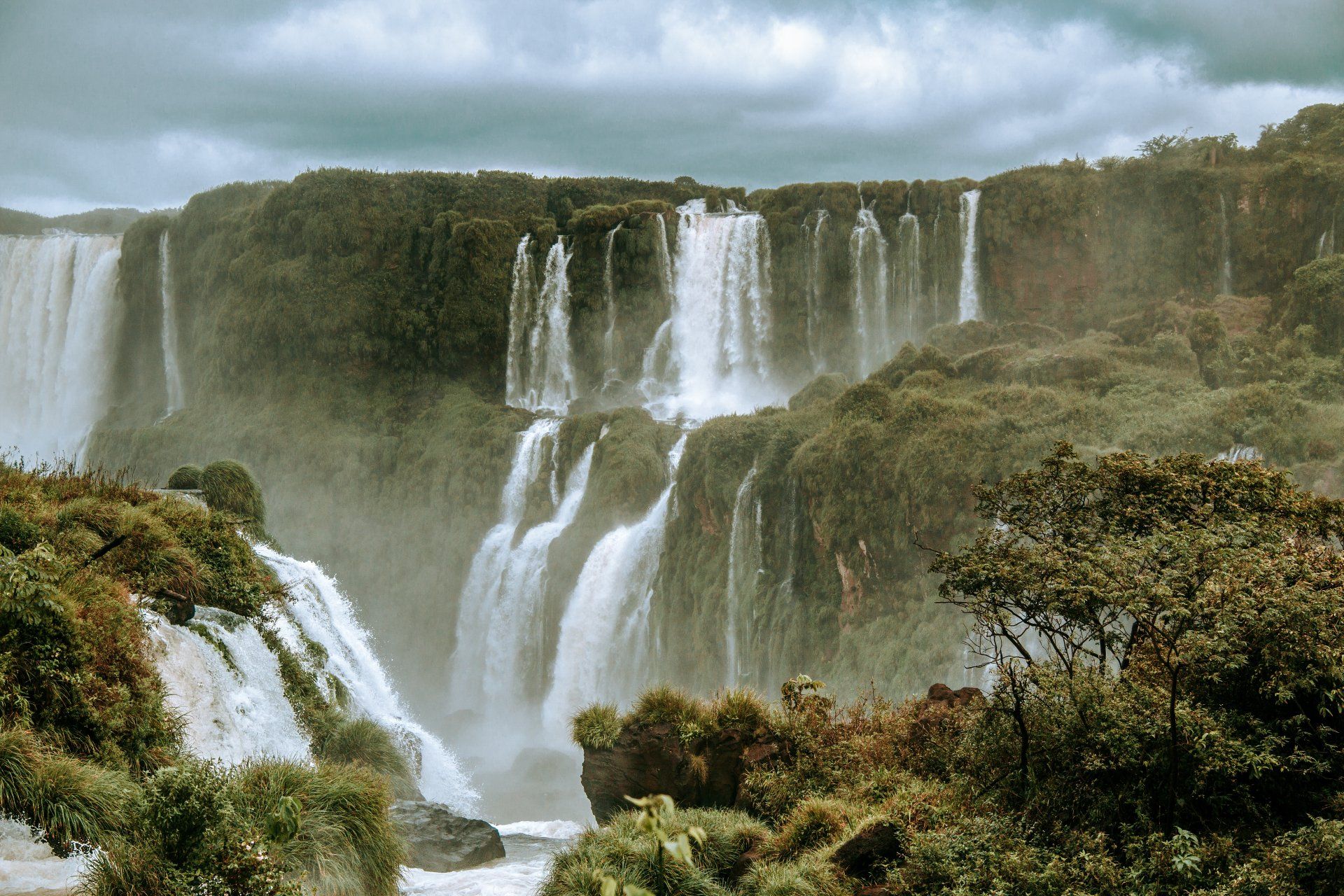 A waterfall in the middle of a forest on a cloudy day