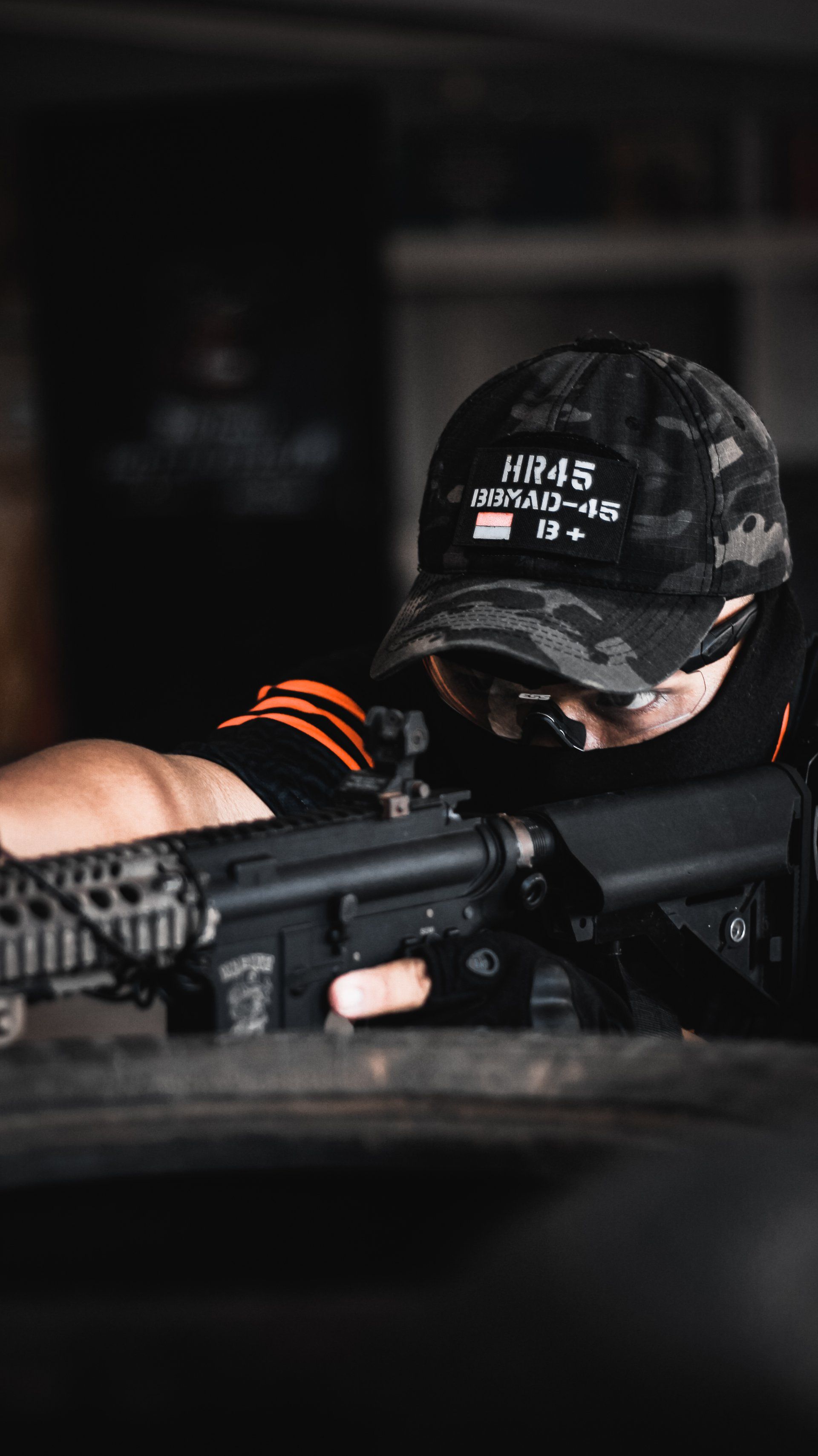 a man wearing a hat that says hr45 on it taking aim with a rifle