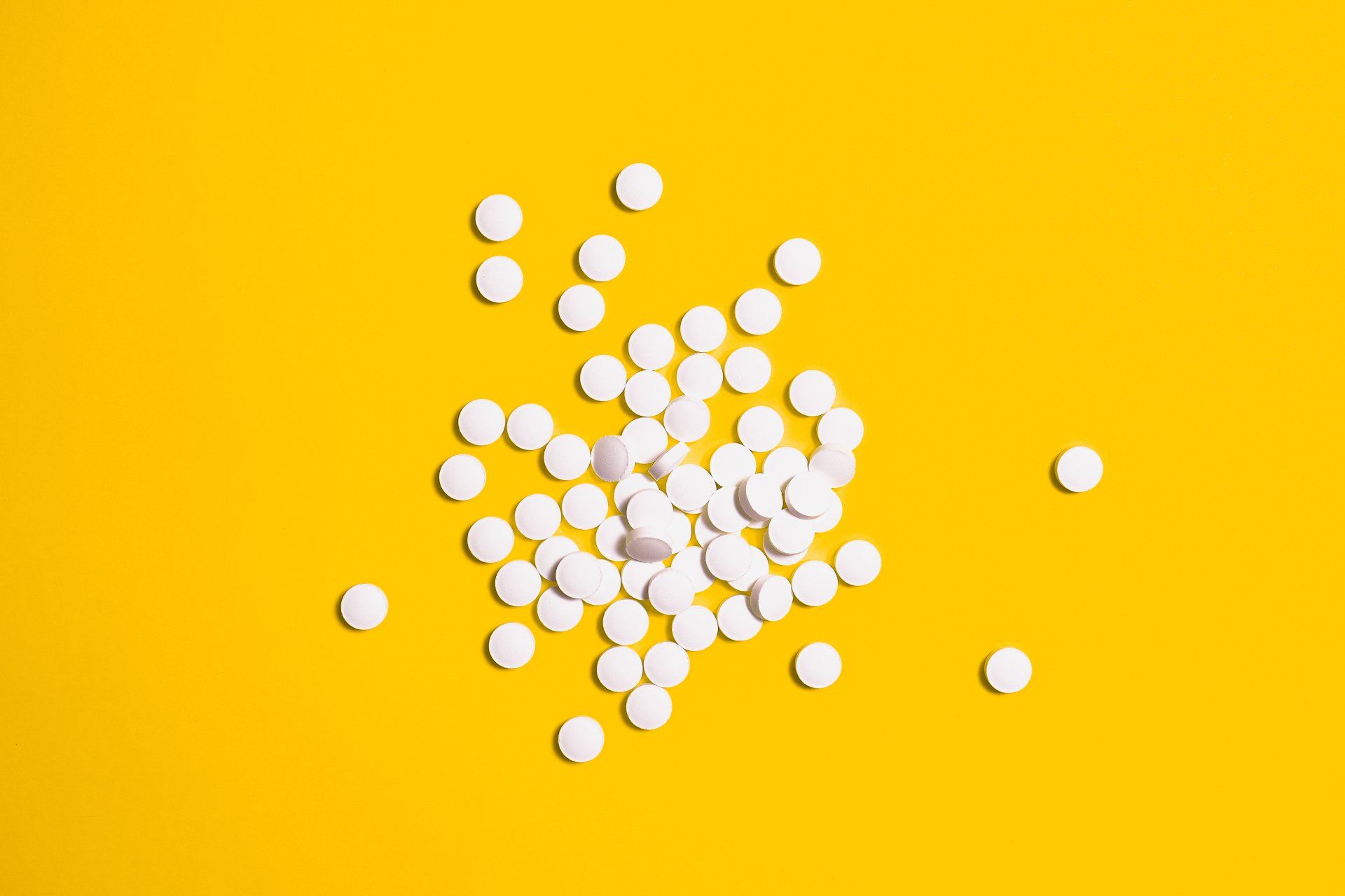 a pile of white pills on a yellow background