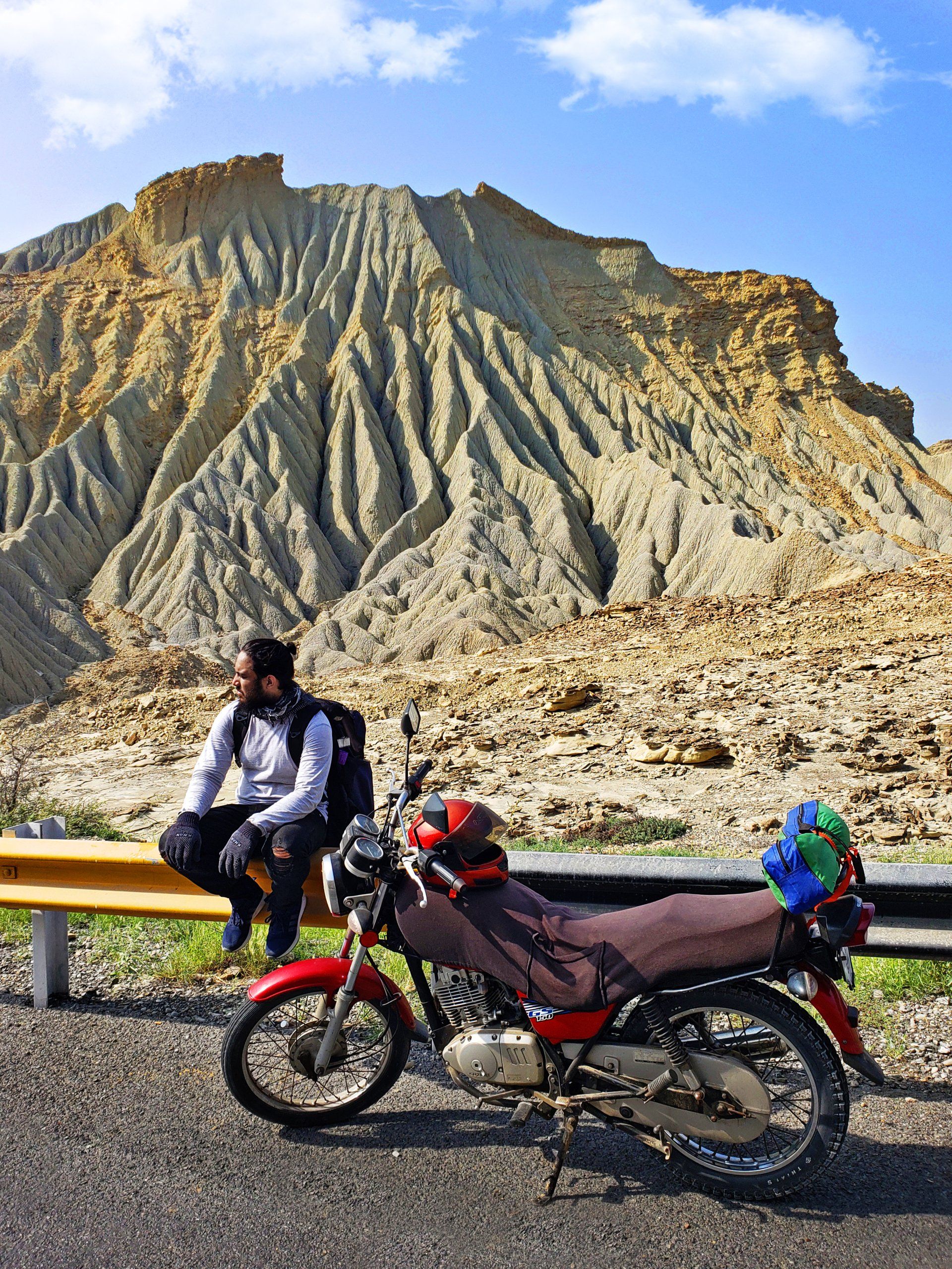 A man is sitting on a bench next to a motorcycle.