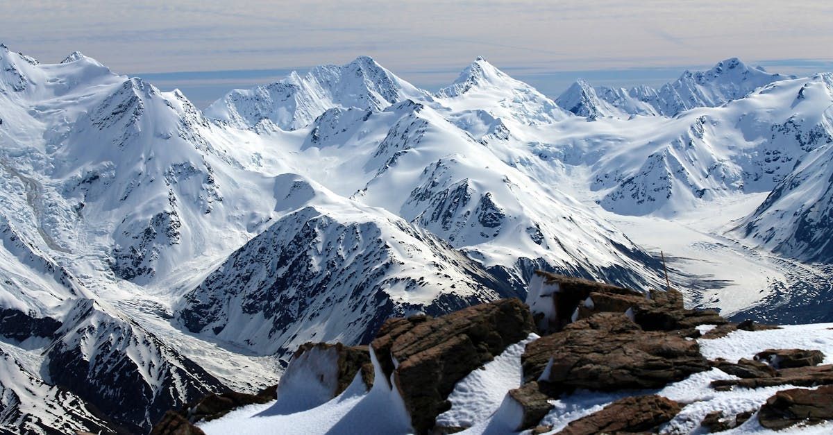 A view of snow covered mountains from the top of a mountain.