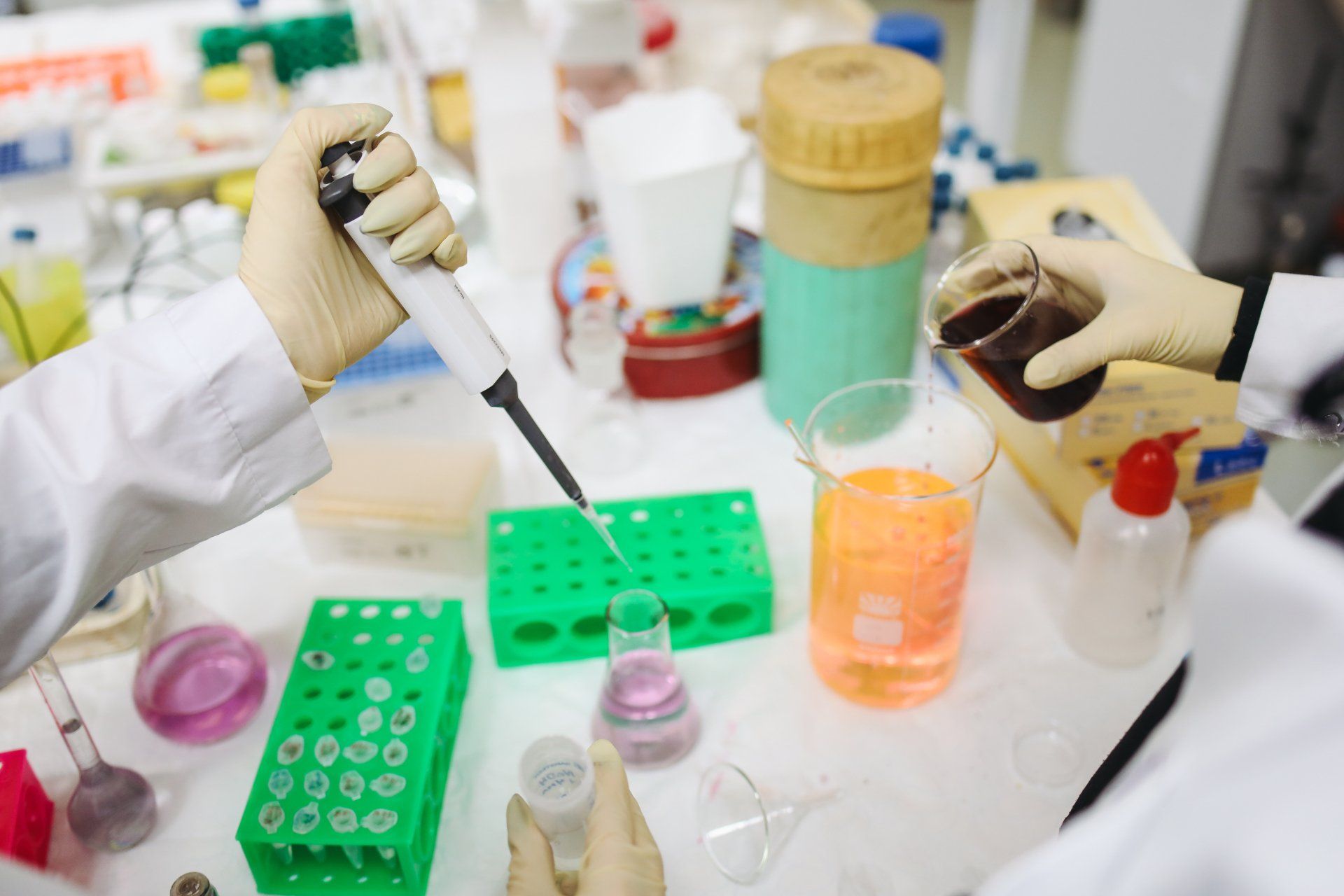 A scientist is using a pipette to pour liquid into a beaker.