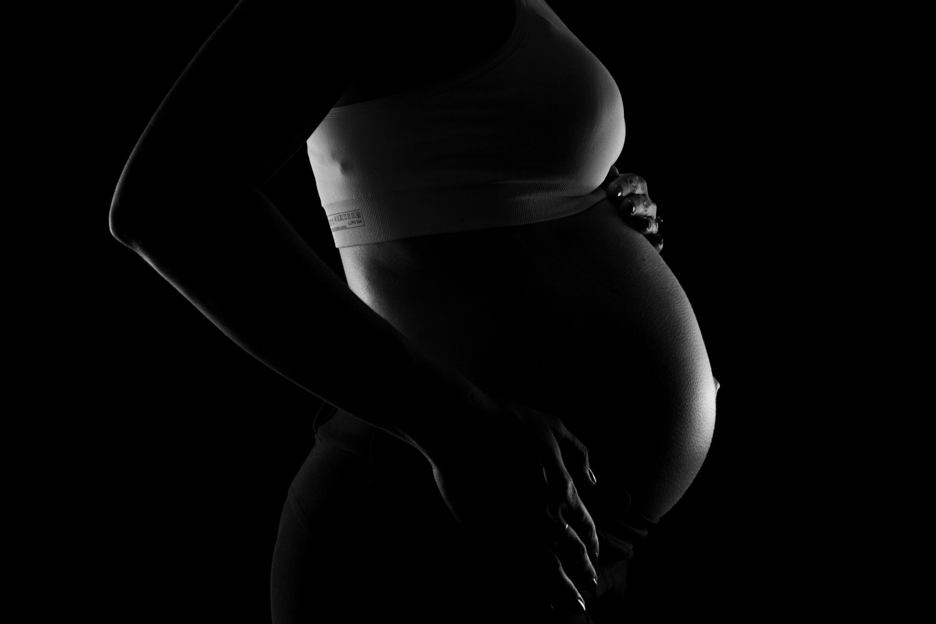 Silouette of an expecting mom. Dramatic lighting. Black and white