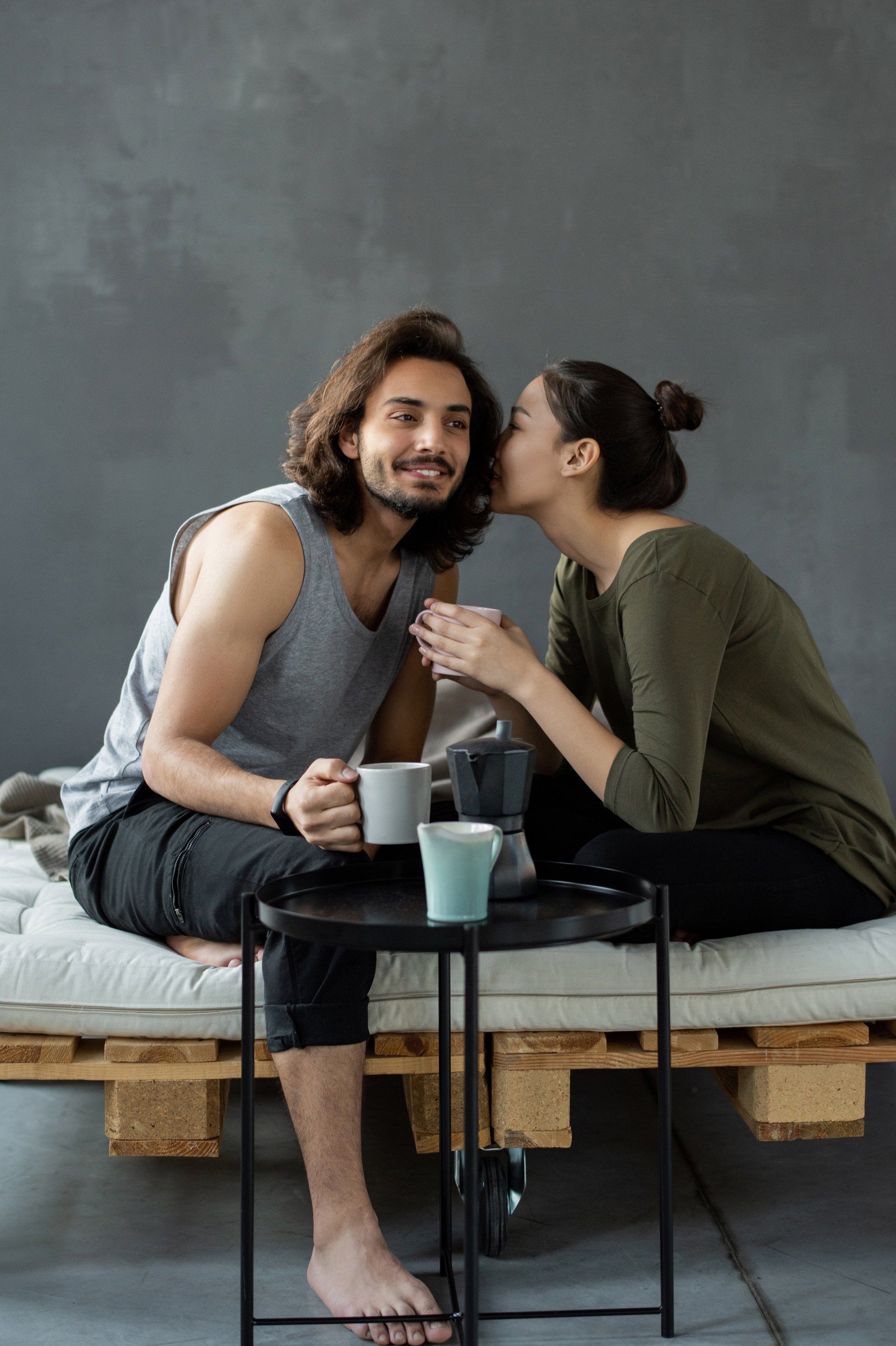 a woman kisses a man on the cheek while they drink coffee 