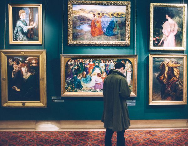 A man is looking at a painting in a museum.