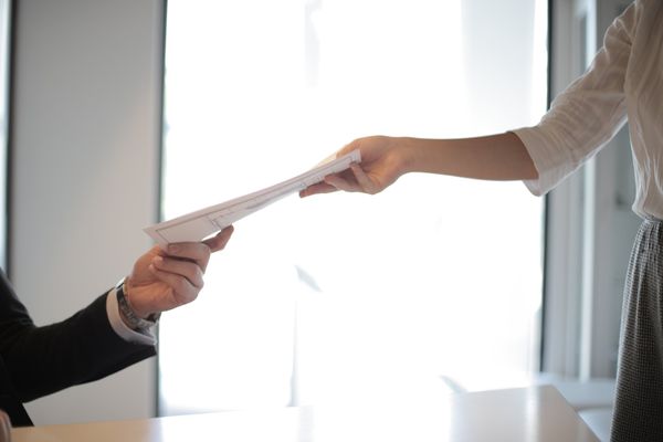 a woman is handing a piece of paper to a man .