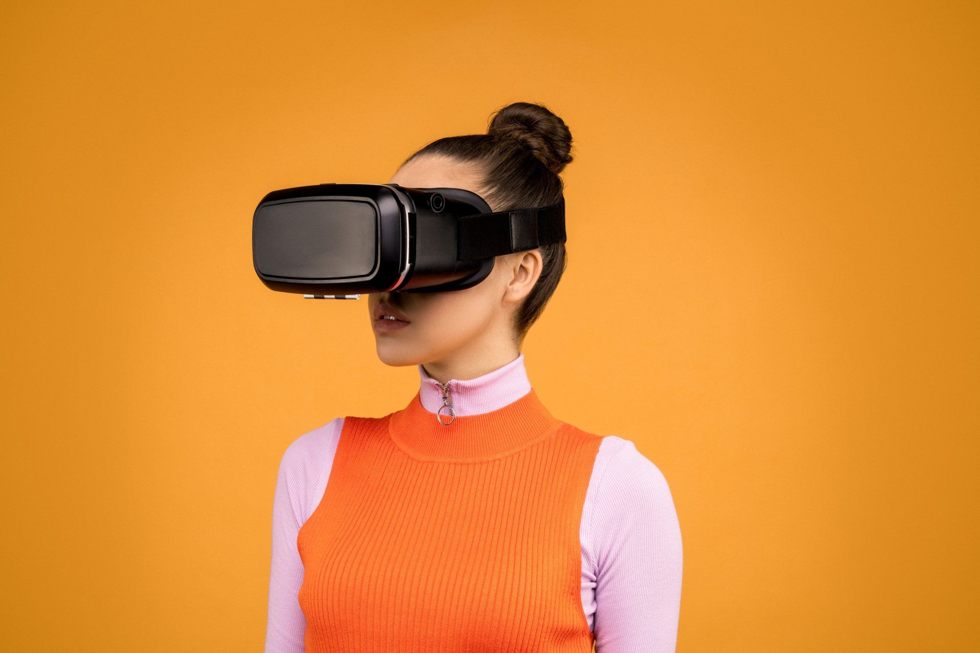 A woman is wearing a virtual reality headset on a yellow background.