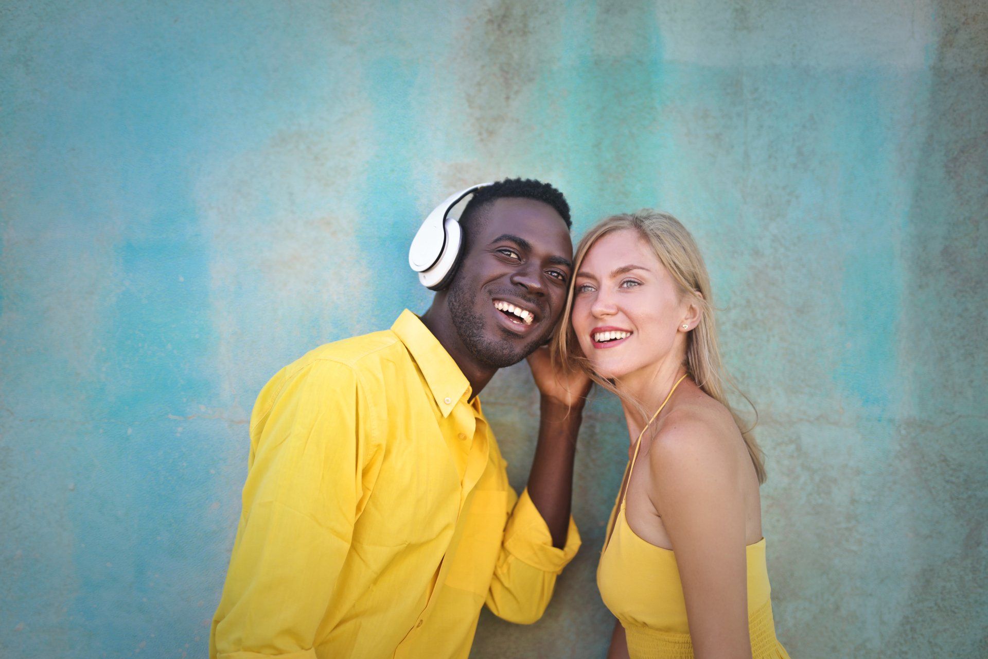 A man and a woman wearing headphones are listening to music together.