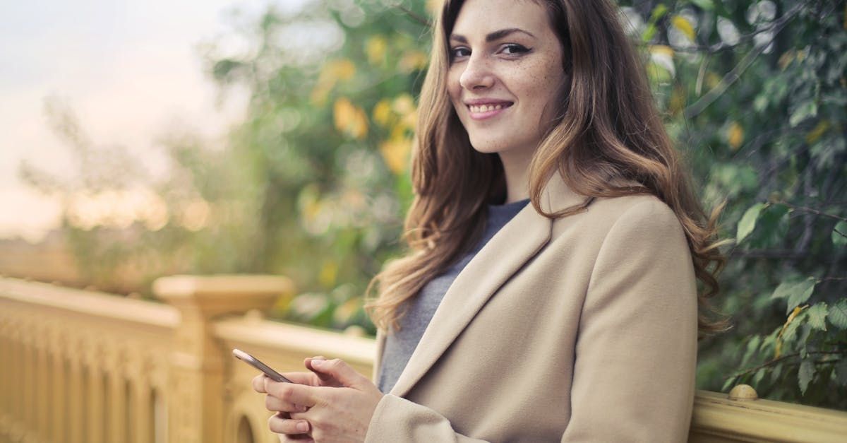 A woman is leaning against a railing while holding a cell phone.