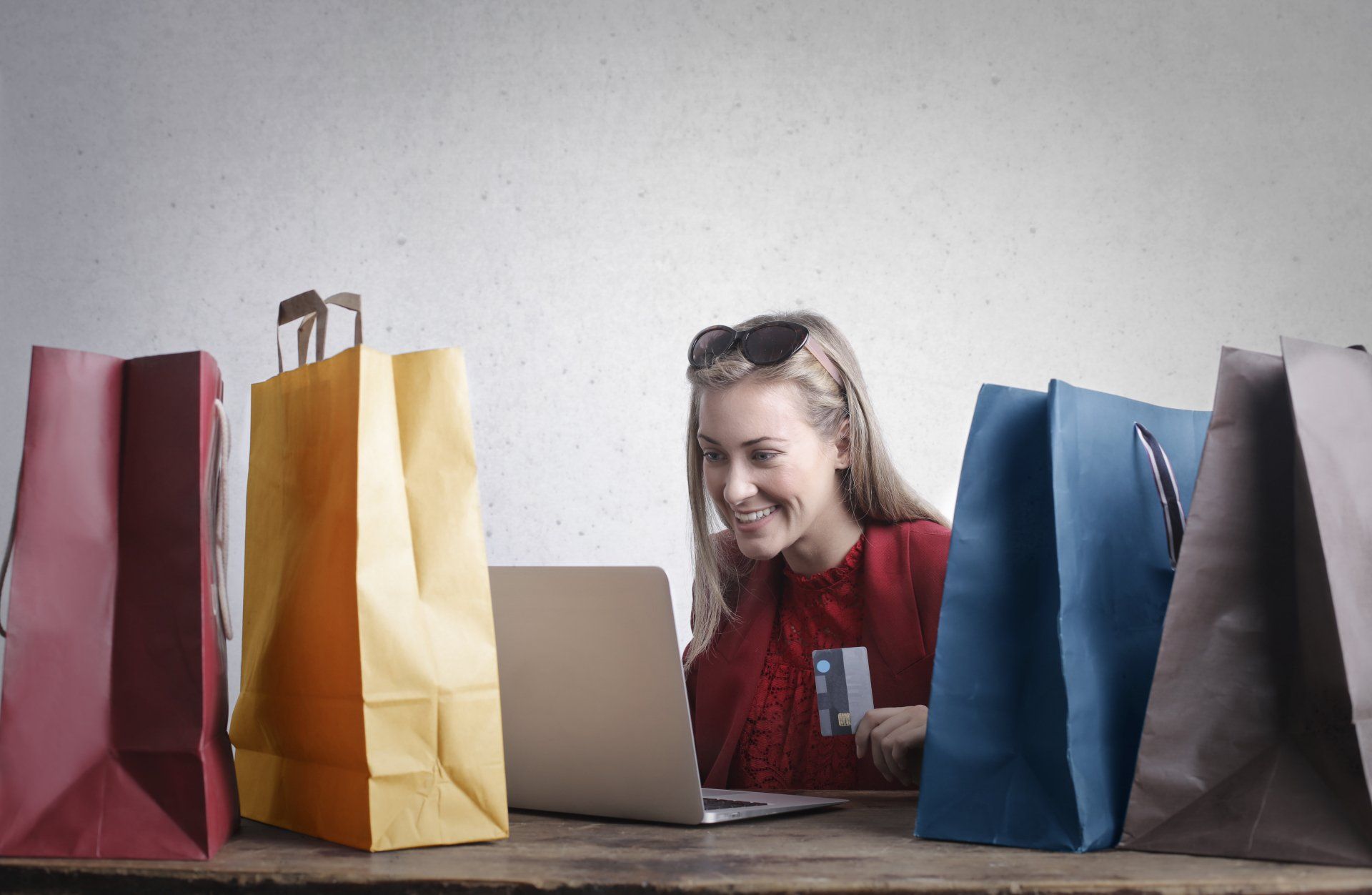 a woman is sitting at a table with shopping bags and a laptop .