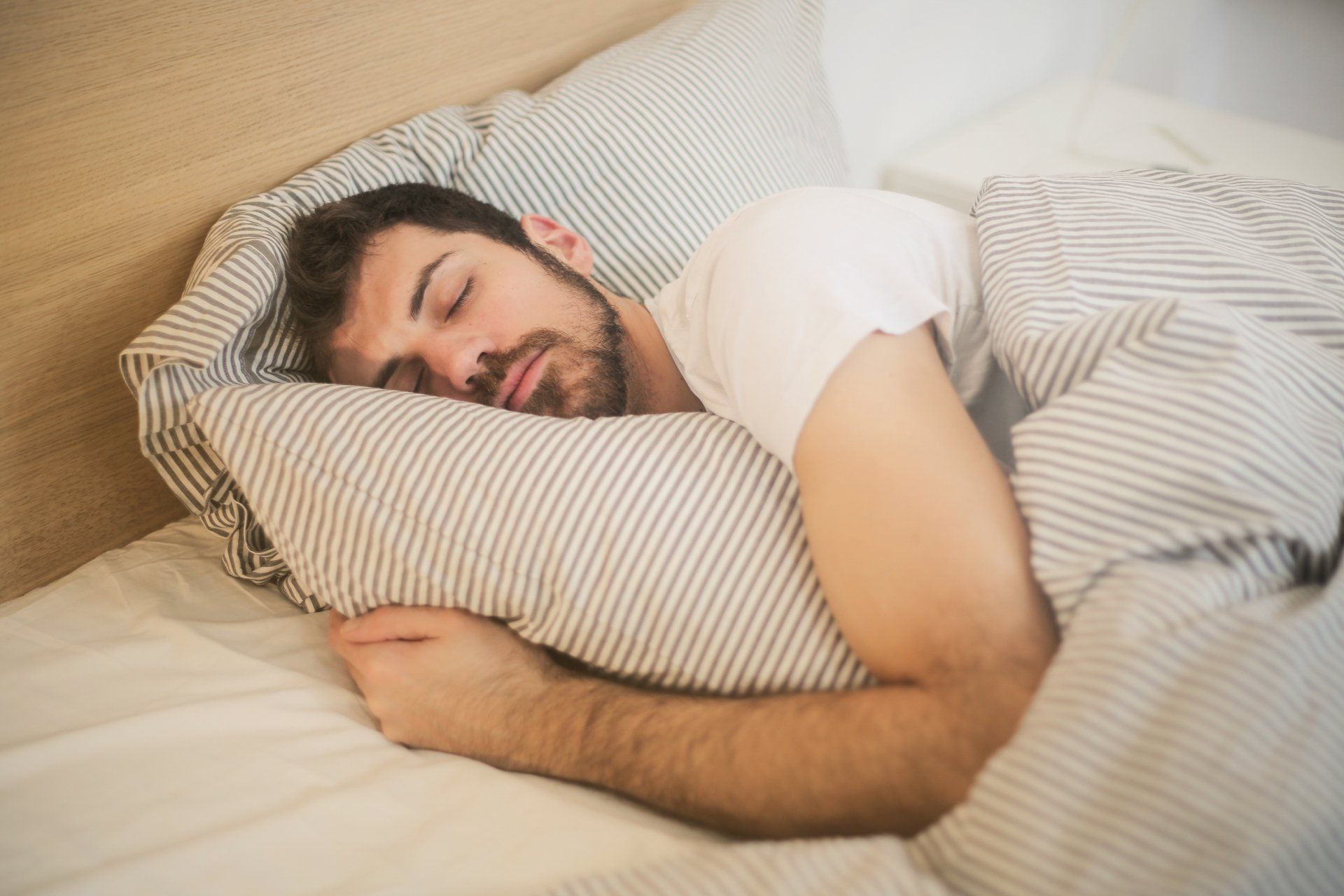 a man is sleeping in a bed with striped sheets and pillows .