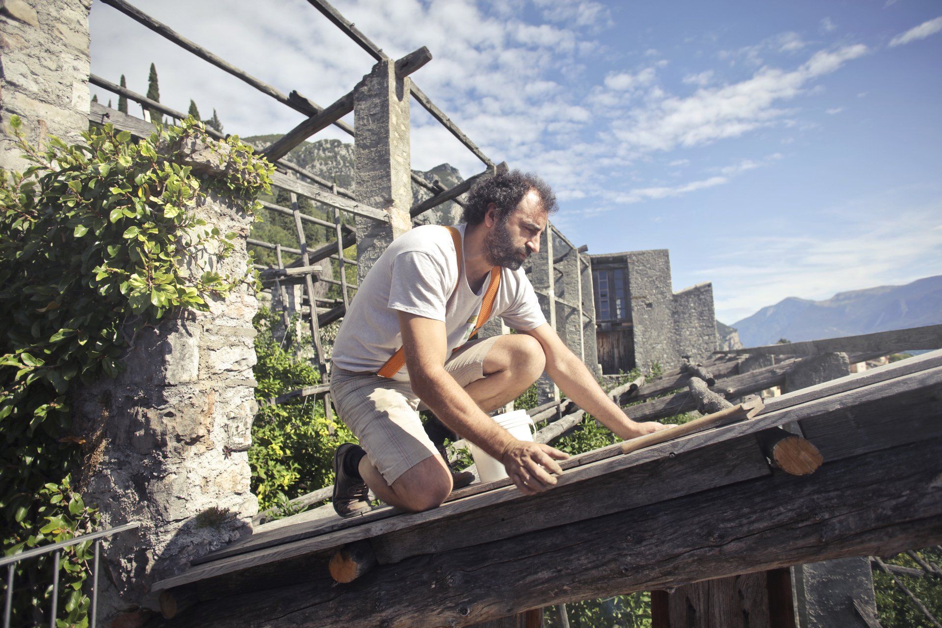 a man is kneeling on the roof of a building without any PPE.