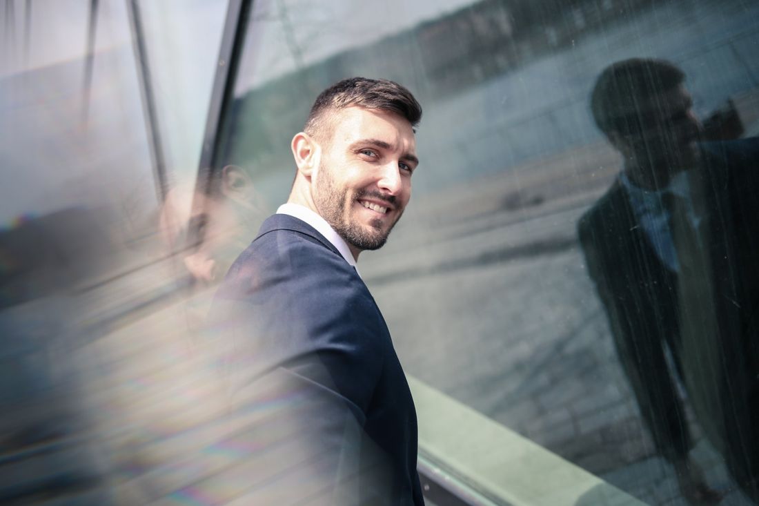 A man in a suit standing in front of a glass building.