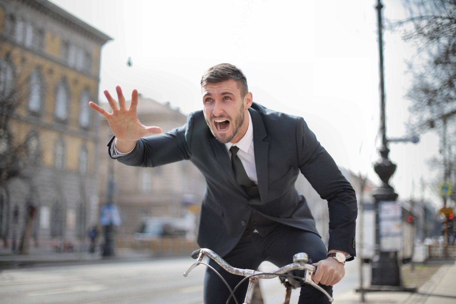 A man in a suit and tie is riding a bicycle down a street.