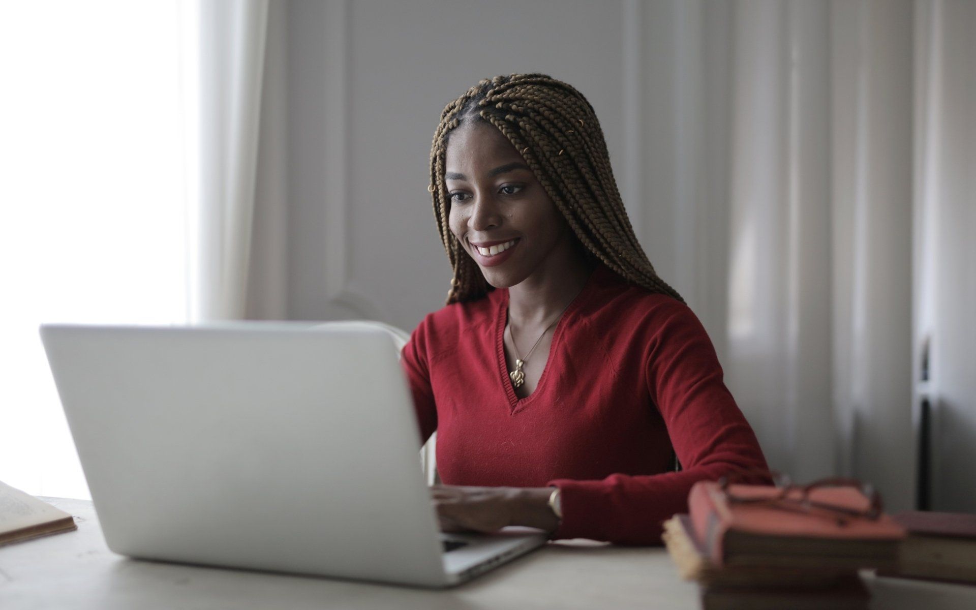 A woman is sitting at a desk using a laptop computer.